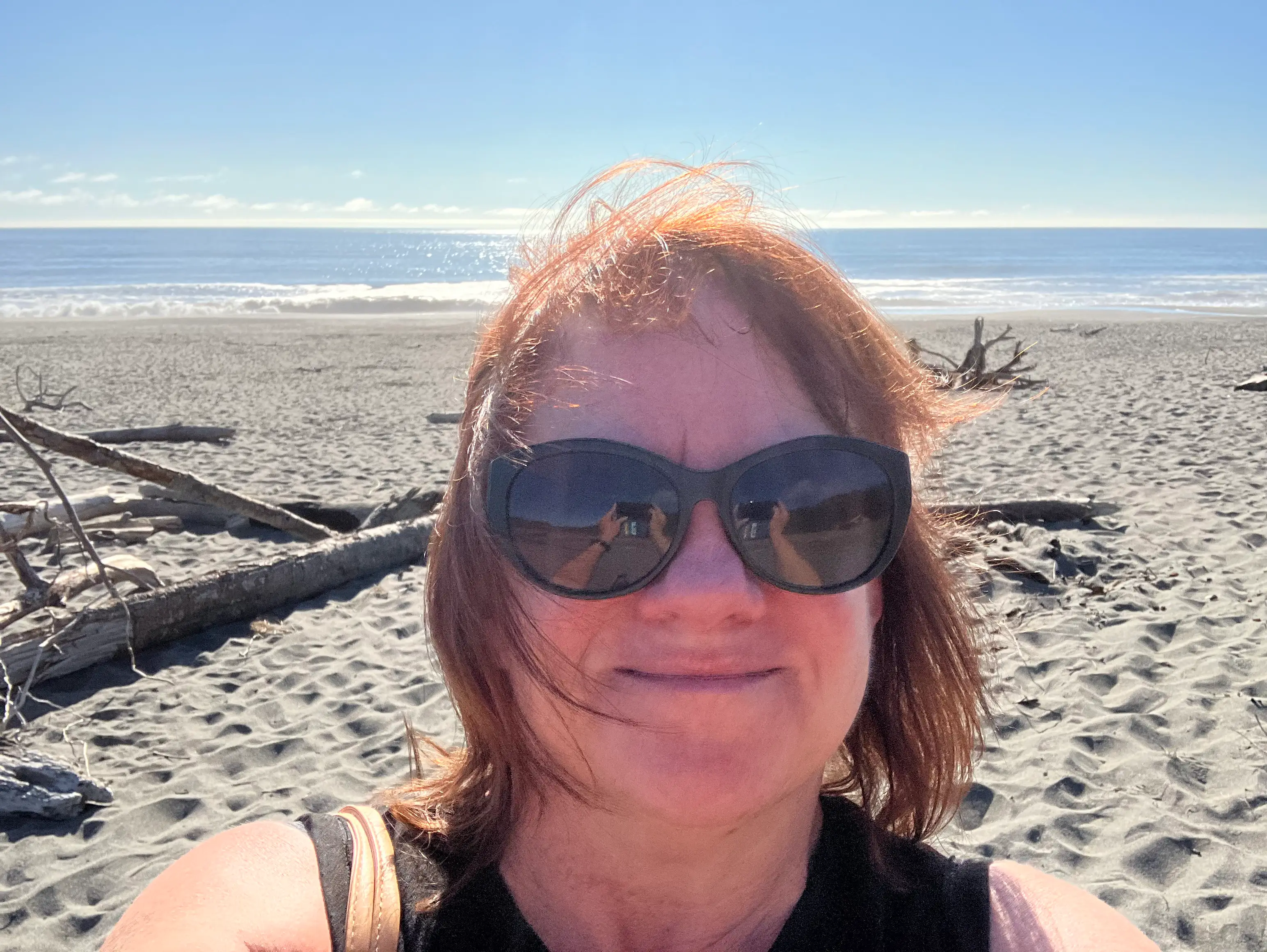 Woman in sunglasses smiling in selfie on beach