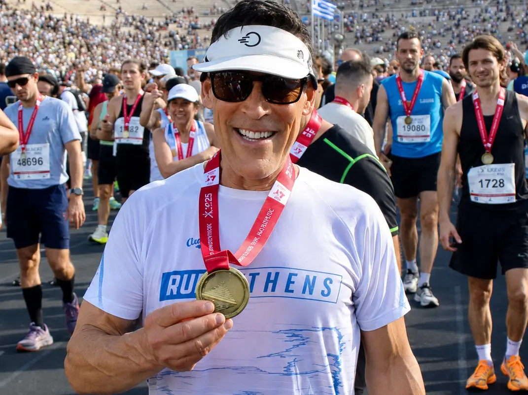 Dean Karnazes holding running medal.