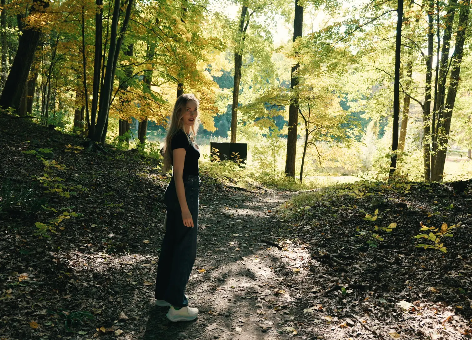 The writer walking along a wooded area with trees in the background.