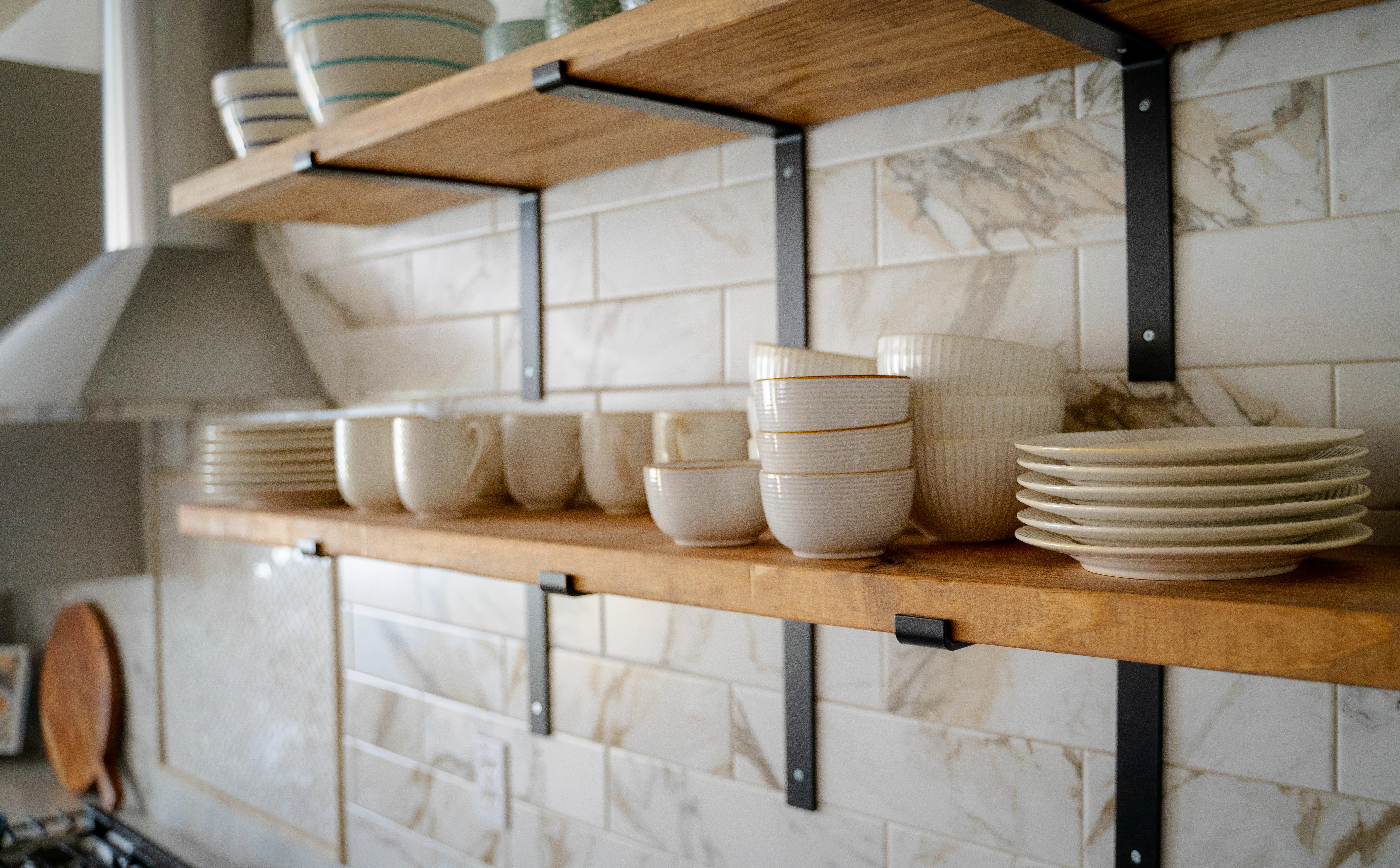 Close up of open kitchen shelves with cups and plates and exhaust hood