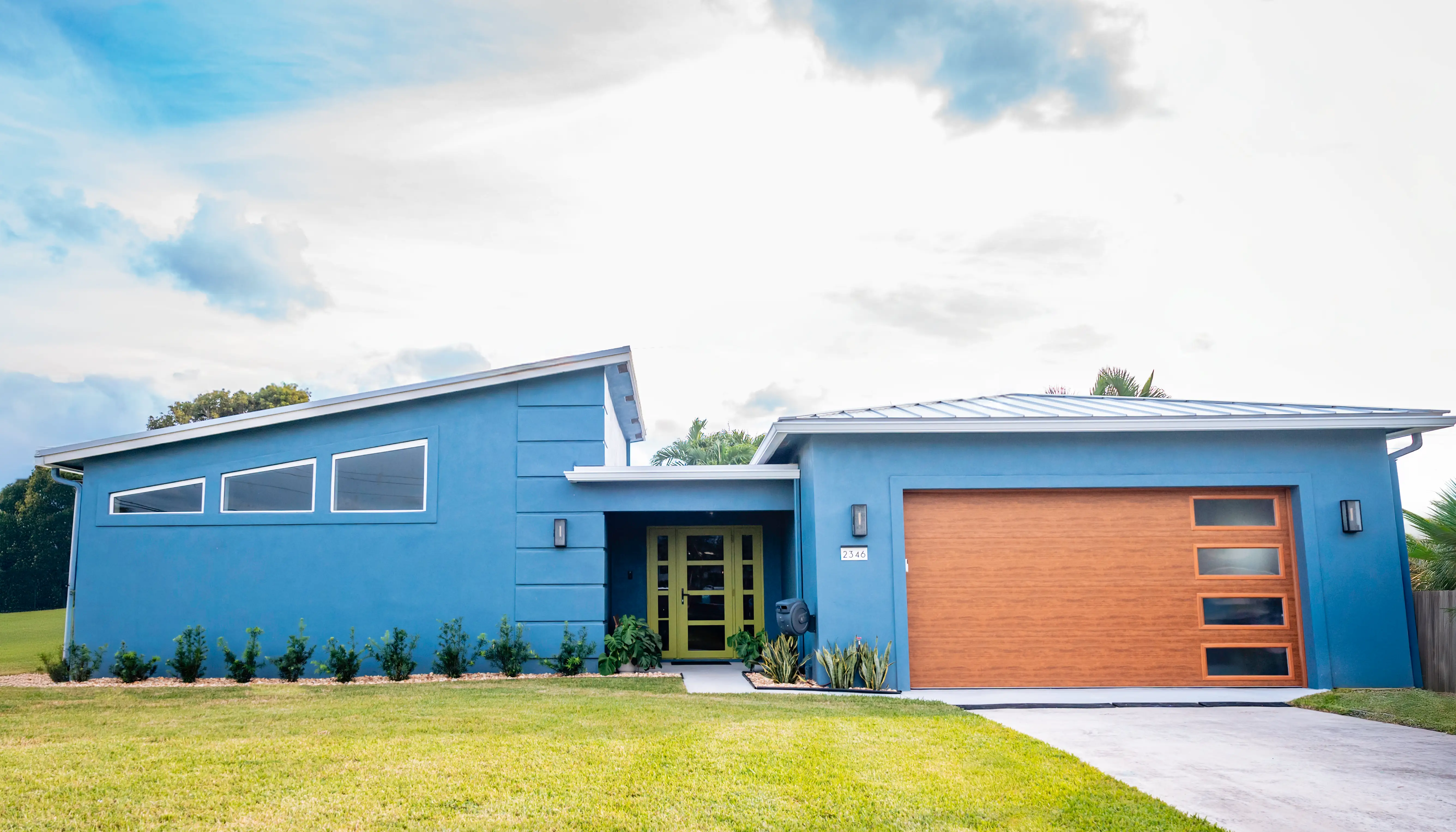 Exteriof of blue one-level midcentury modern home with wood garage
