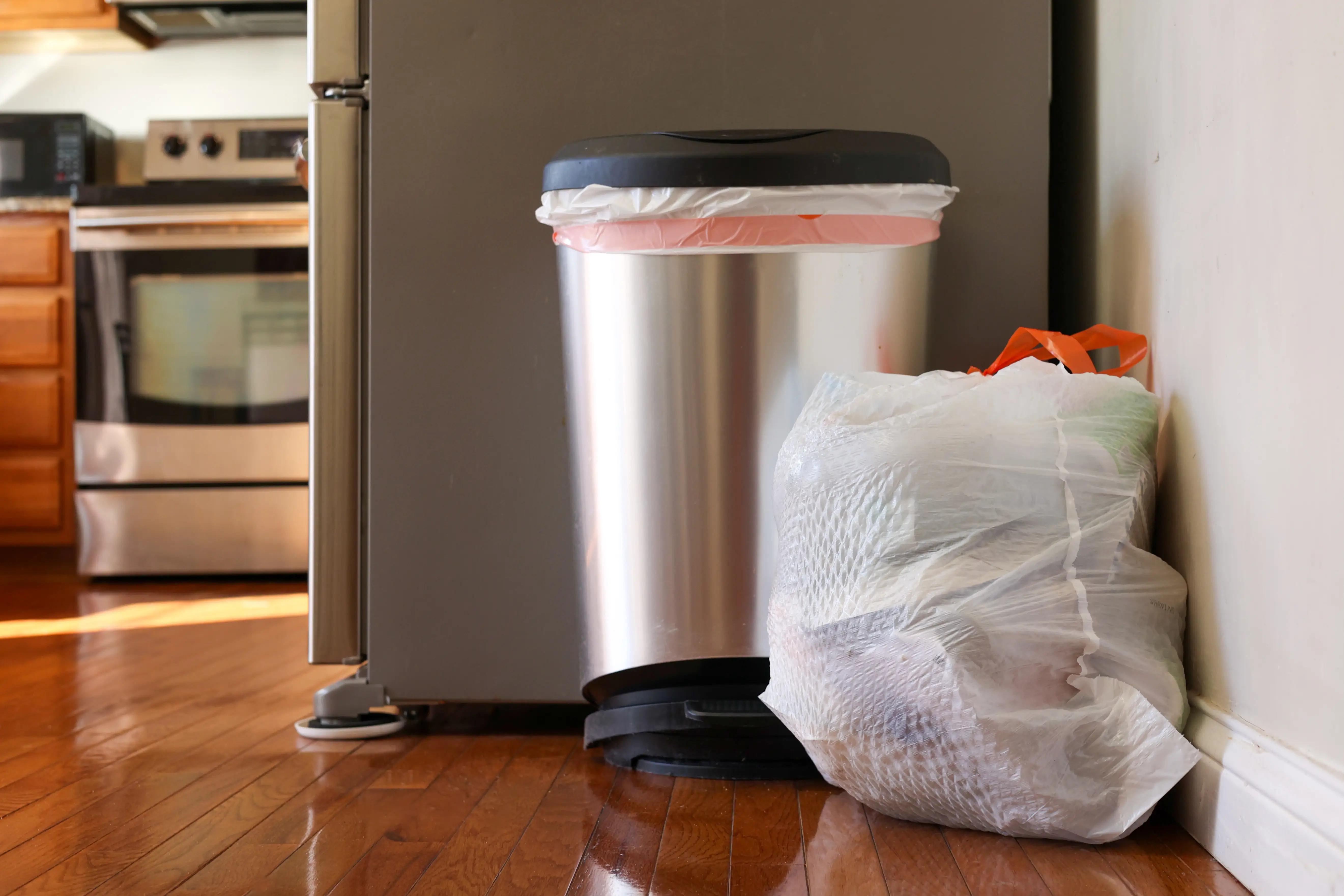 Trash can and garbage bag on floor of kitchen