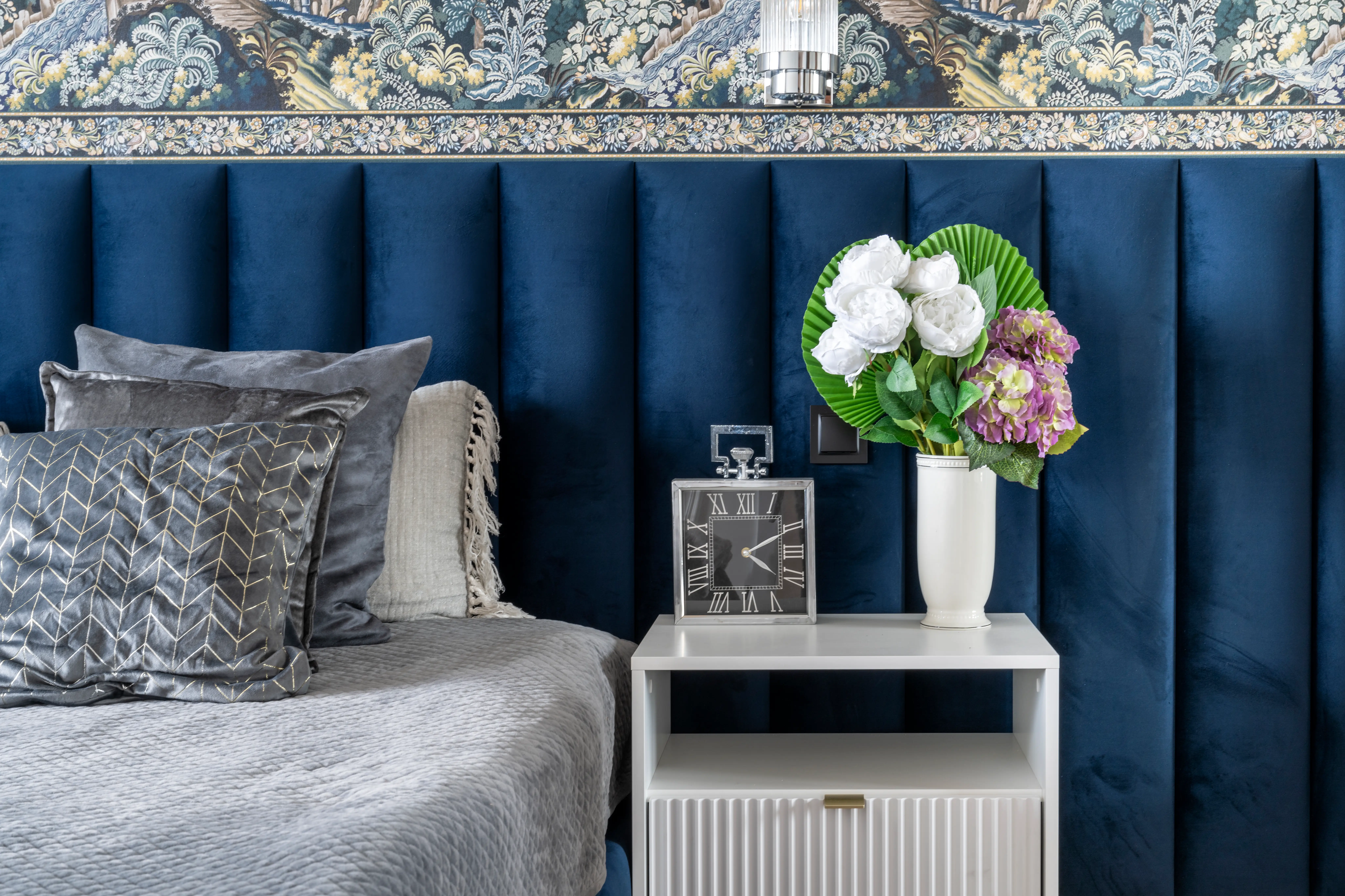 Bedroom with white side table, blue velvet wall, decorate wallpaper