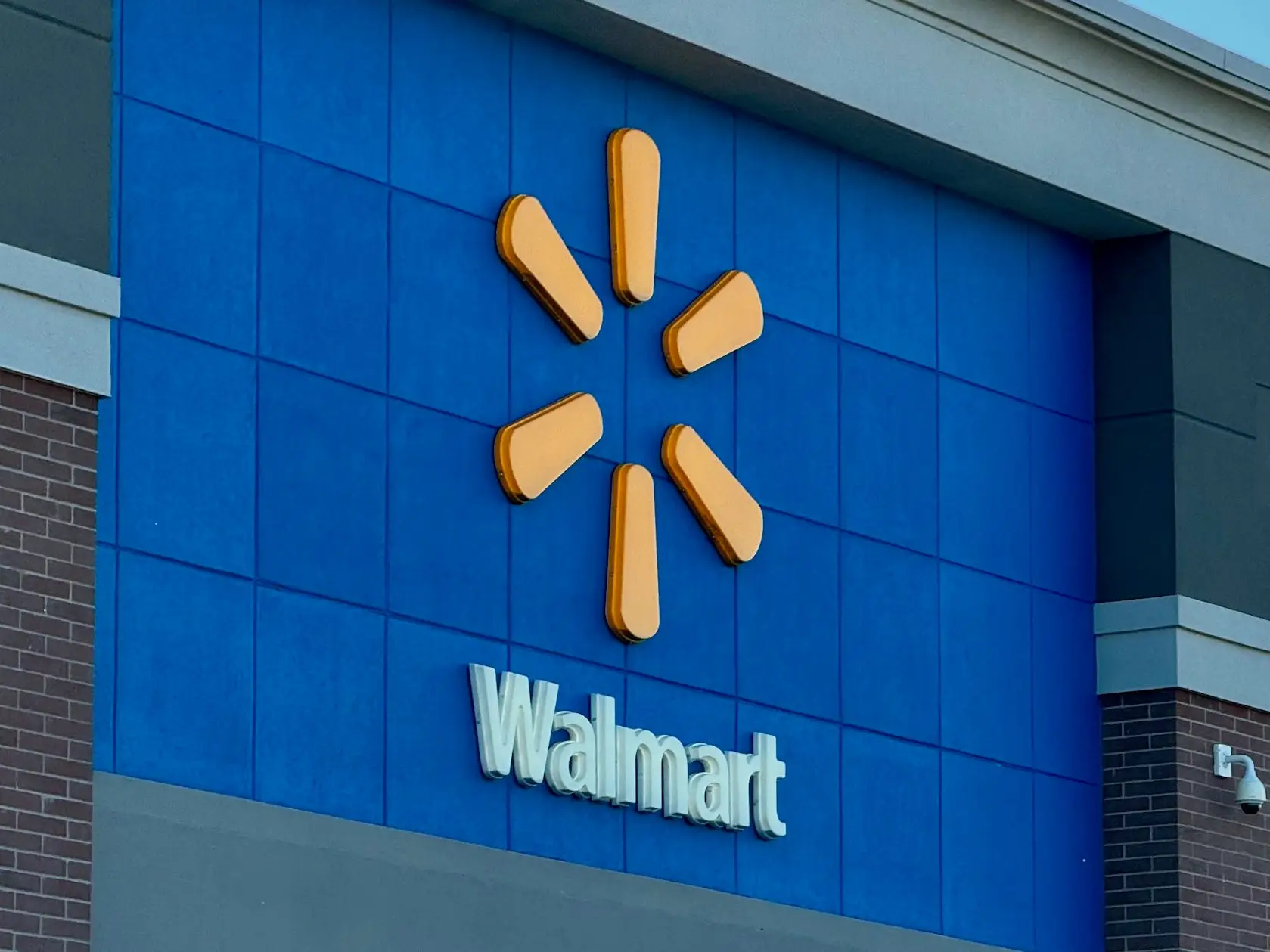Walmart storefront exterior shows the spark logo above signs reading “Walmart” and “Outdoor.”