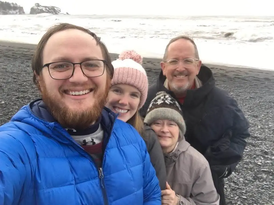 Laura Grace and her husband pose for a photo with his parents on a beach in Olympic National Park.