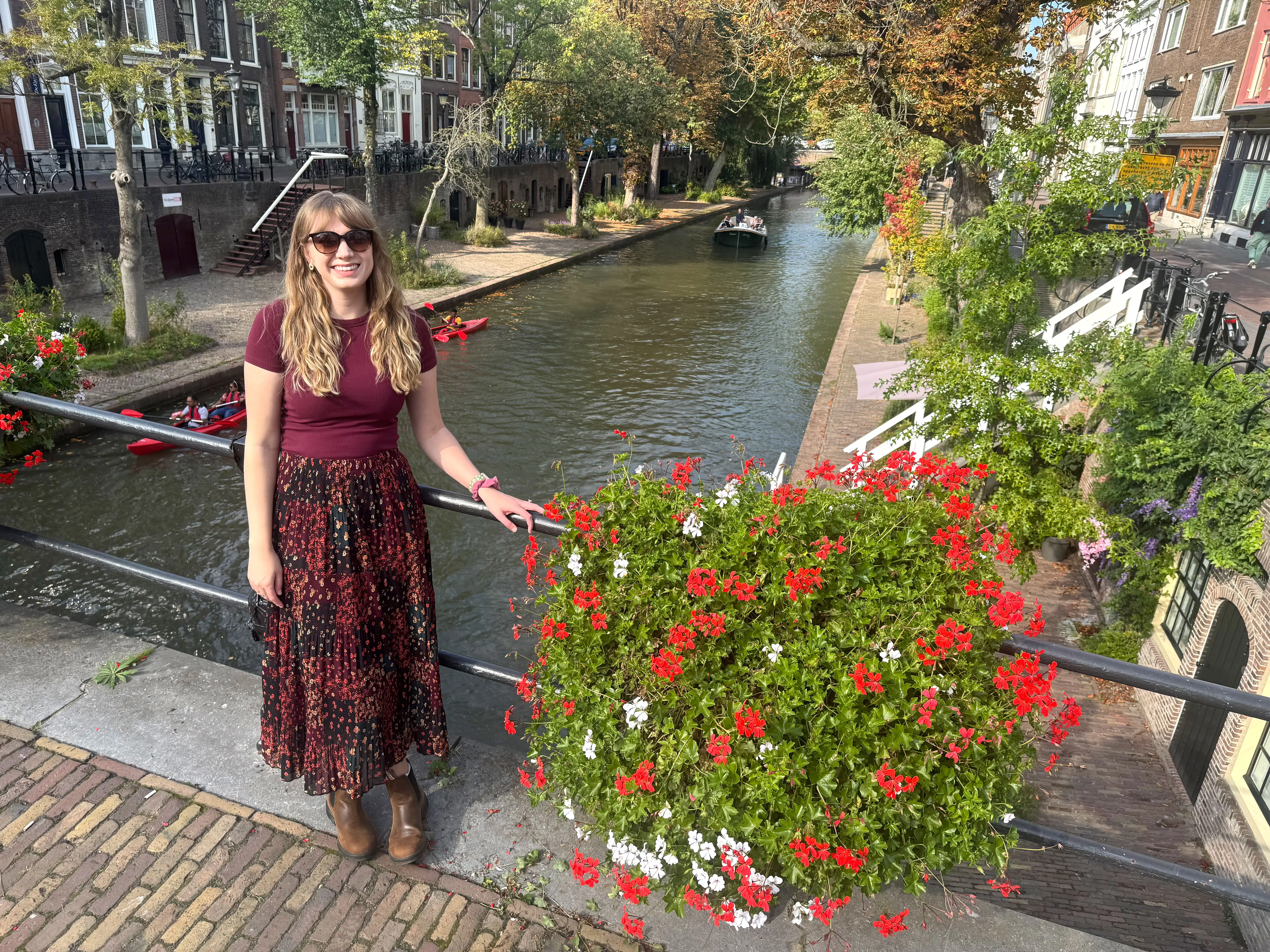 Emily stands on a bridge over a canal that's lined with homes and trees.