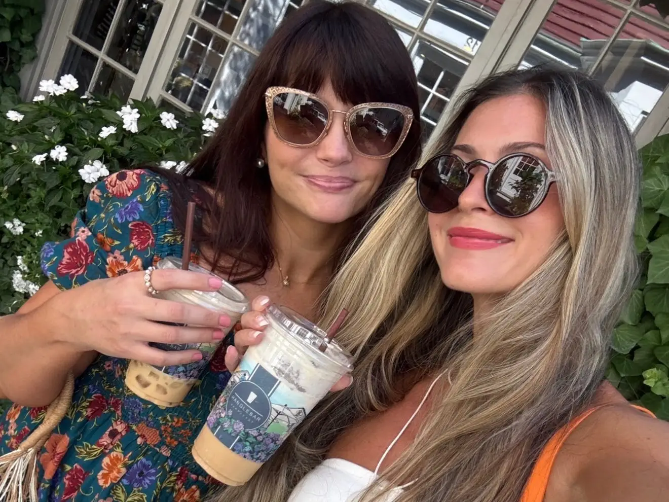 Two women smiling, holding coffee drinks