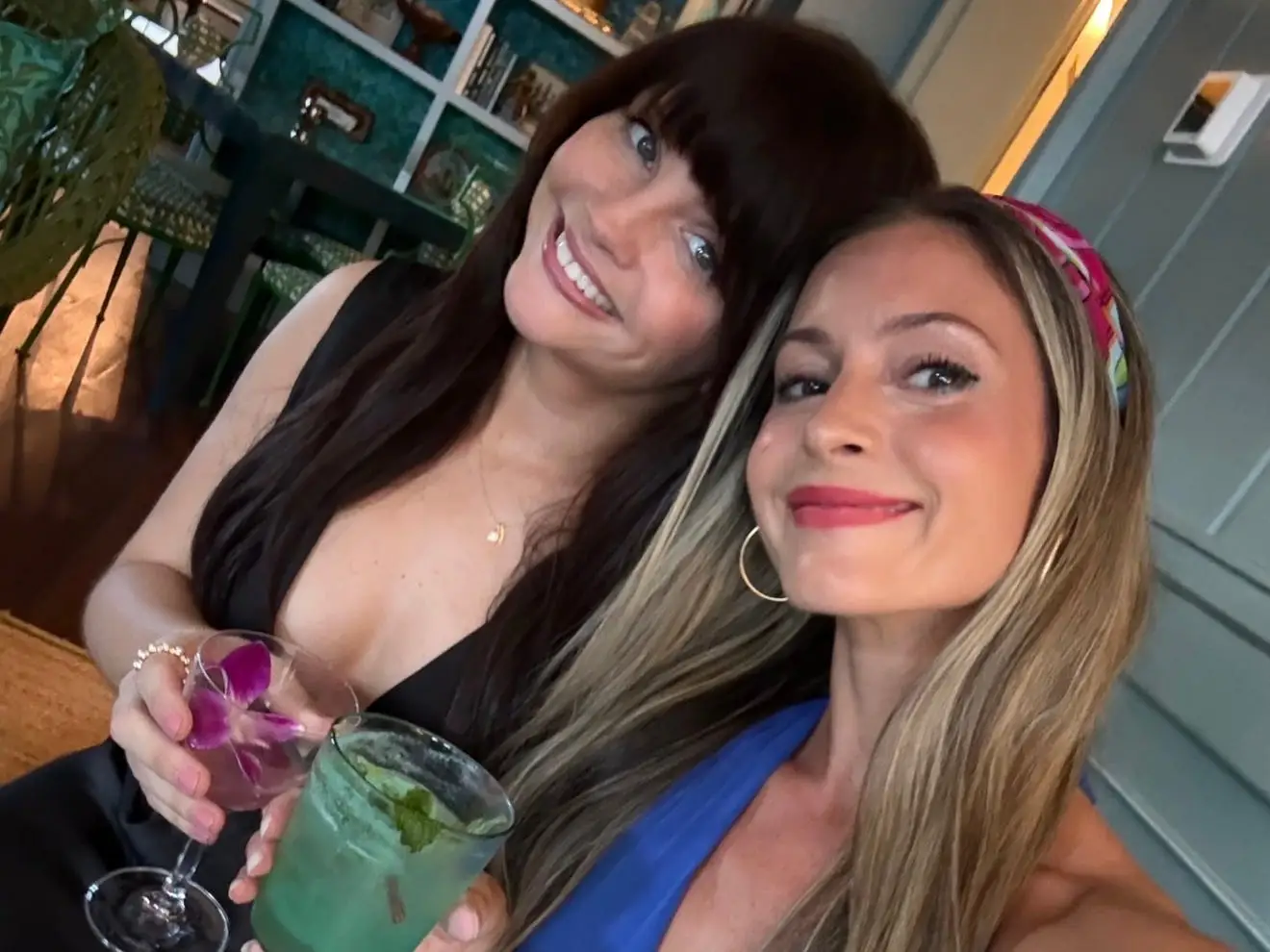 Two women smiling, holding cocktails