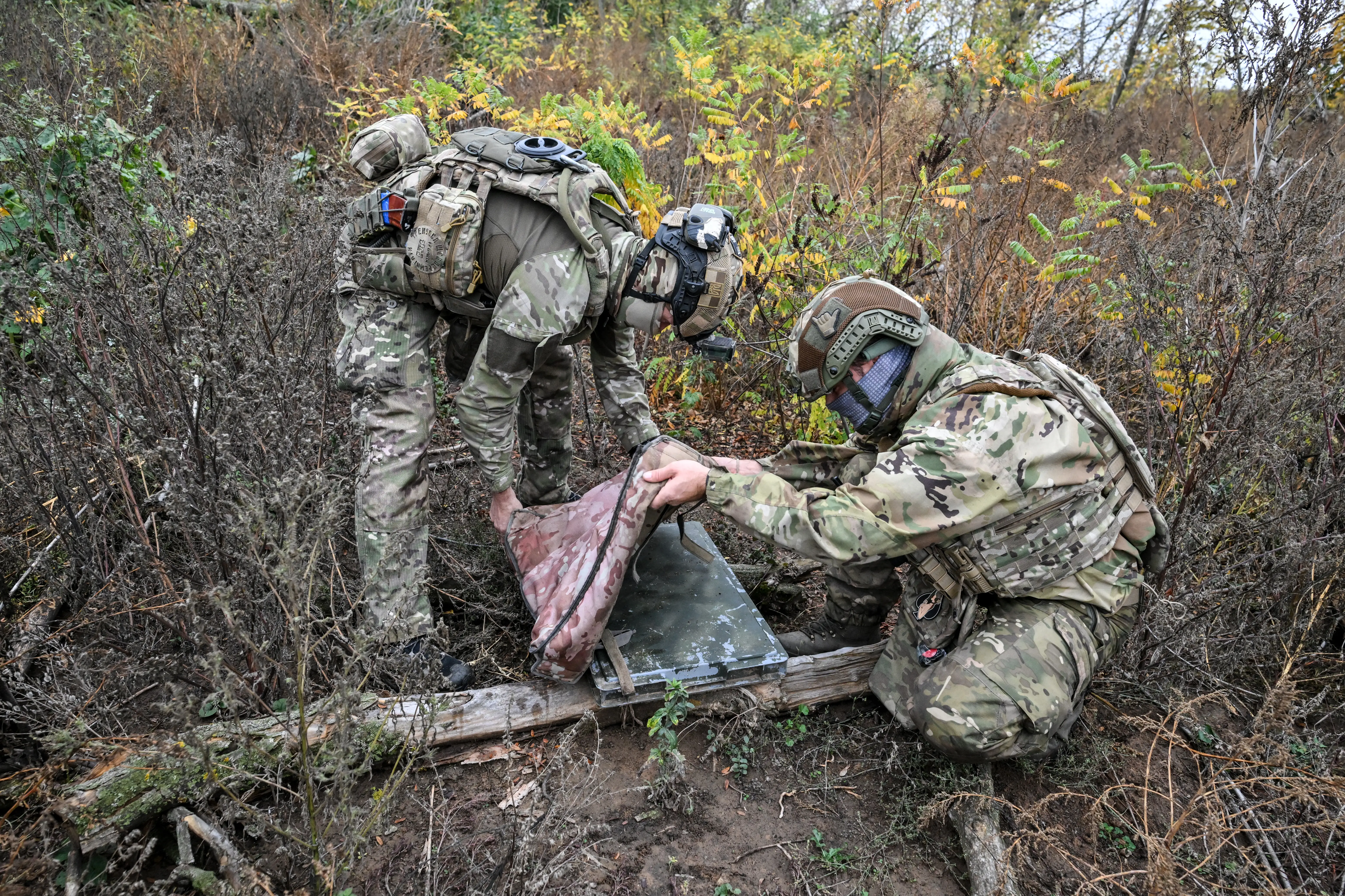 Soldiers from a separate task rifle battalion of the National Police of Ukraine in the Zaporizhzhia region use a camouflage case to protect a Starlink satellite communication terminal from Russian aerial reconnaissance in the Donetsk region, Ukraine, on October 16, 2026.