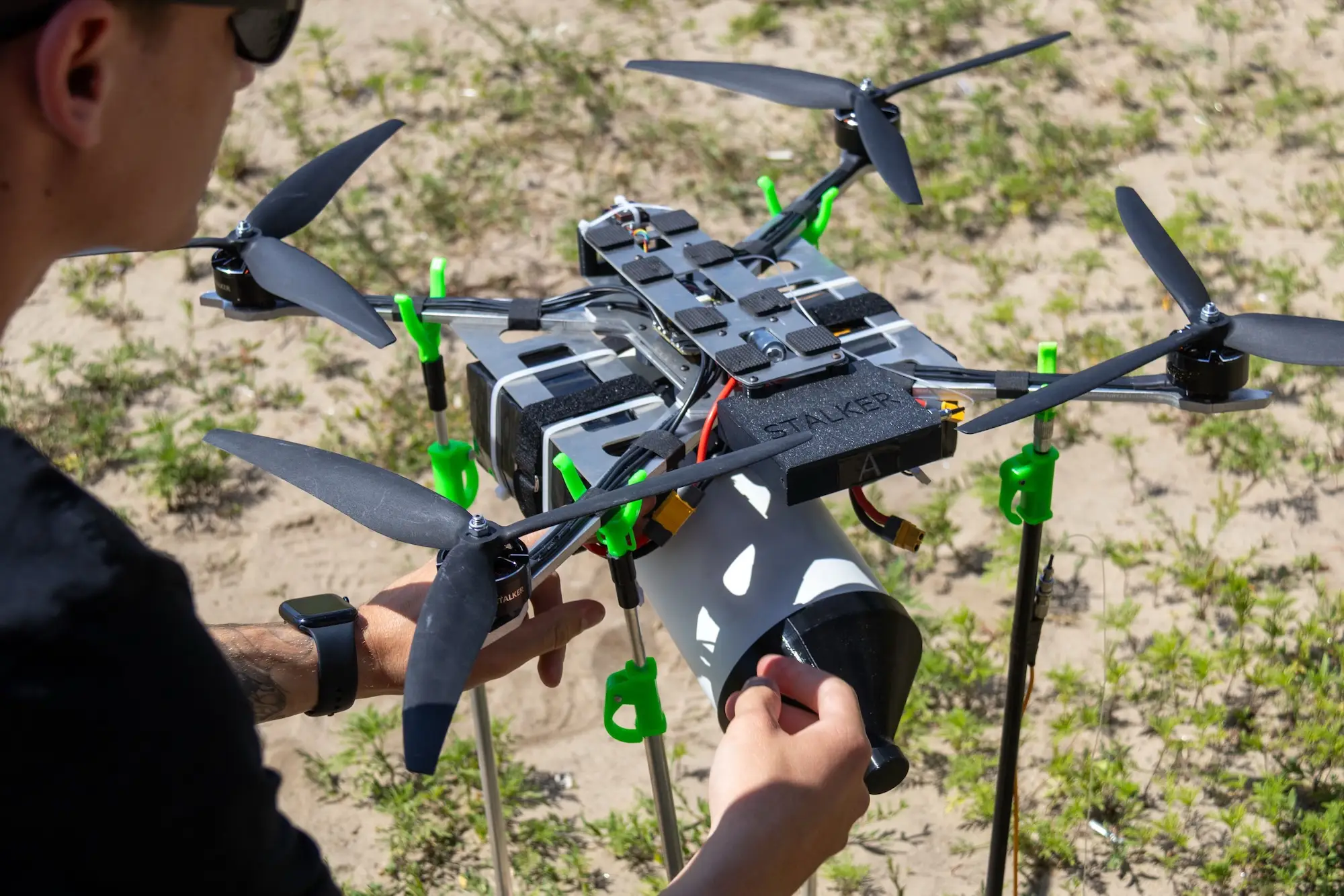 A person adjusts a multirotor drone with a sensor payload on an outdoor stand.