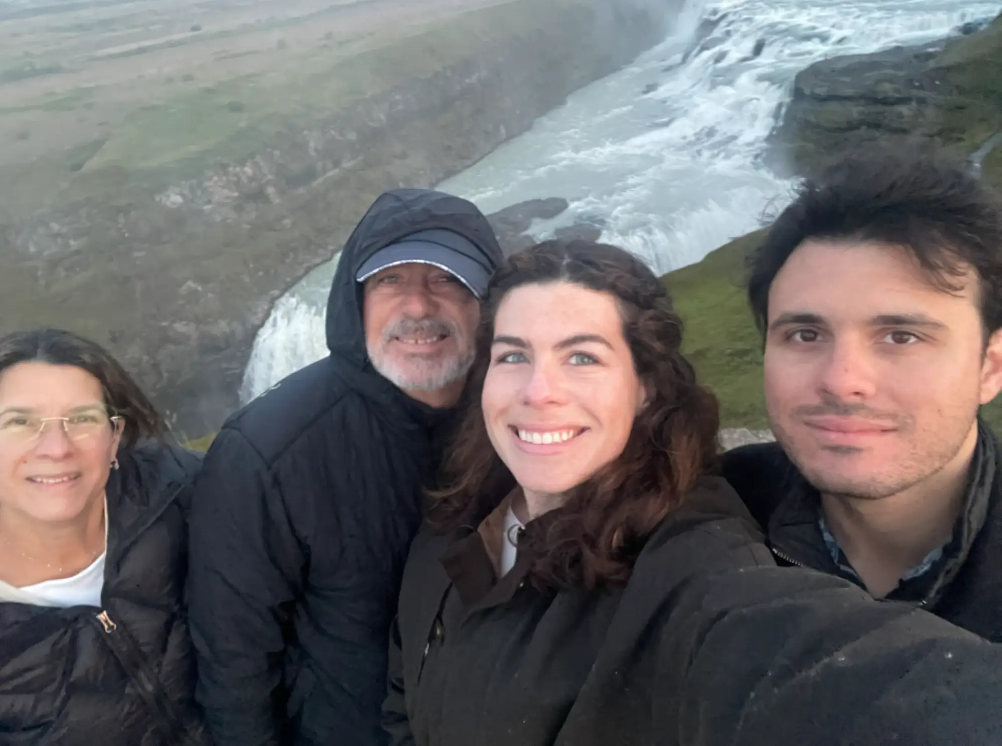 A family by a waterfall in Iceland all wearing black jackets.