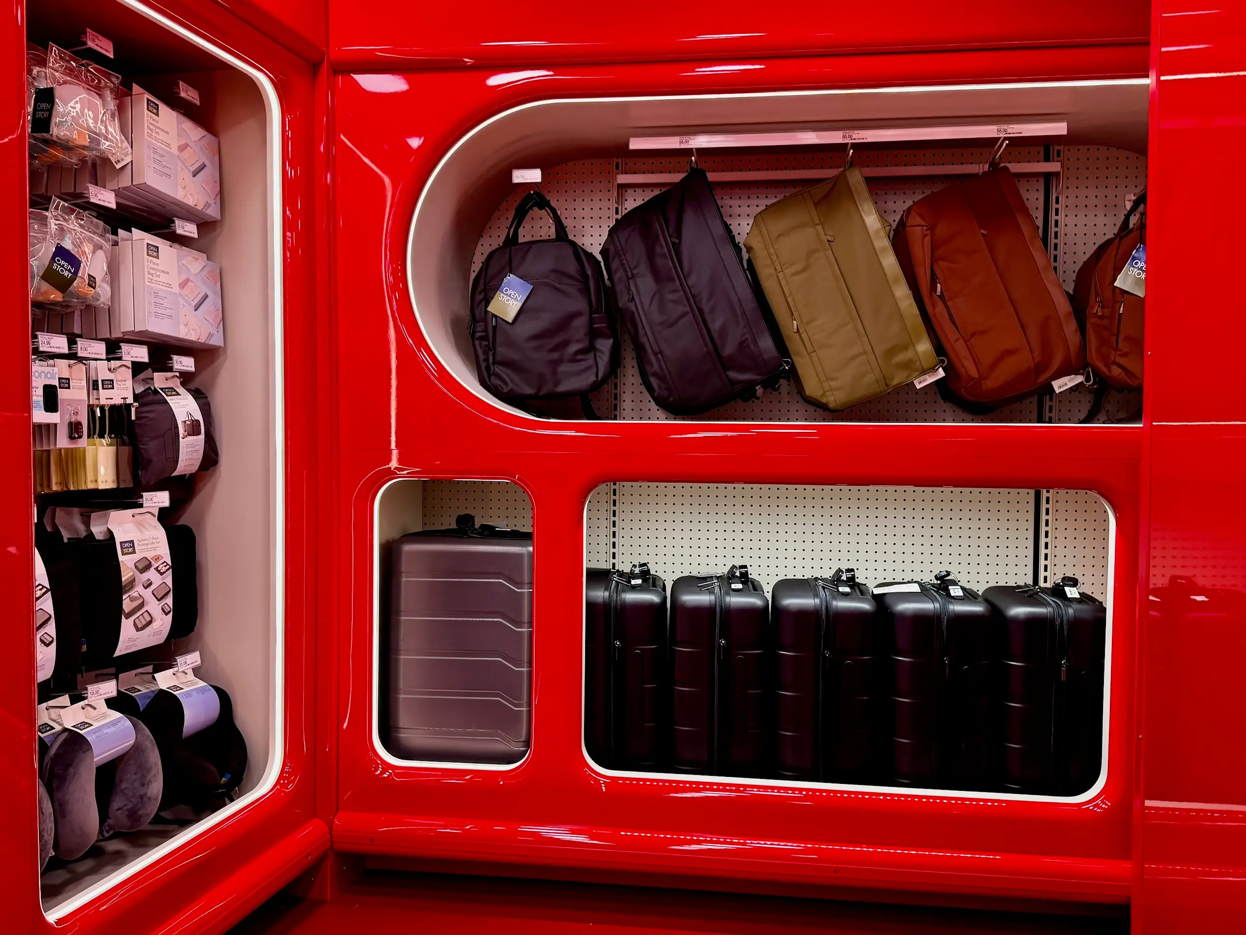 Backpacks, suitcases, and travel accessories are displayed in glossy red retail shelving.