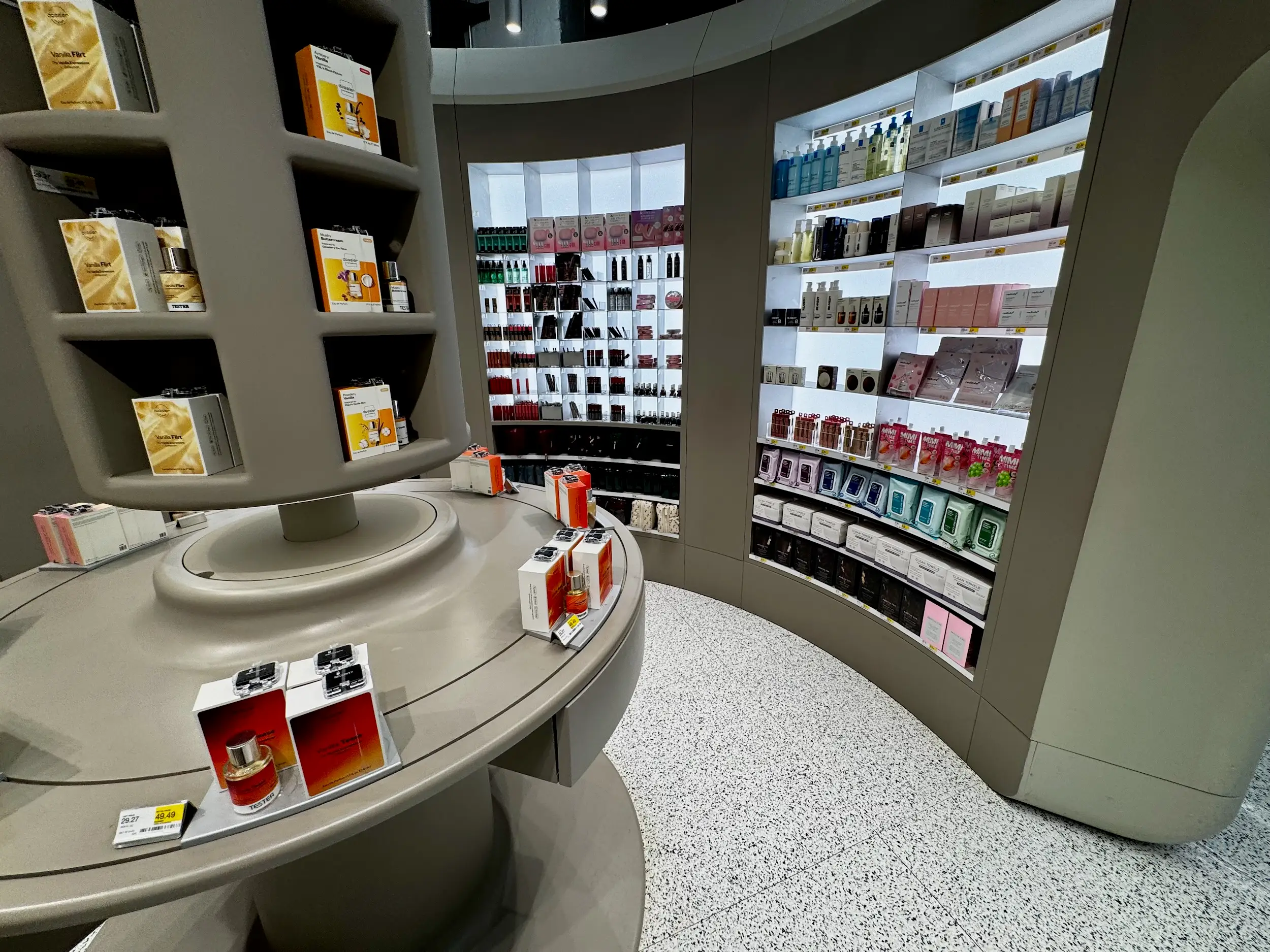 Curved shelves display boxed perfumes and beauty products inside a brightly lit cosmetics retail store.