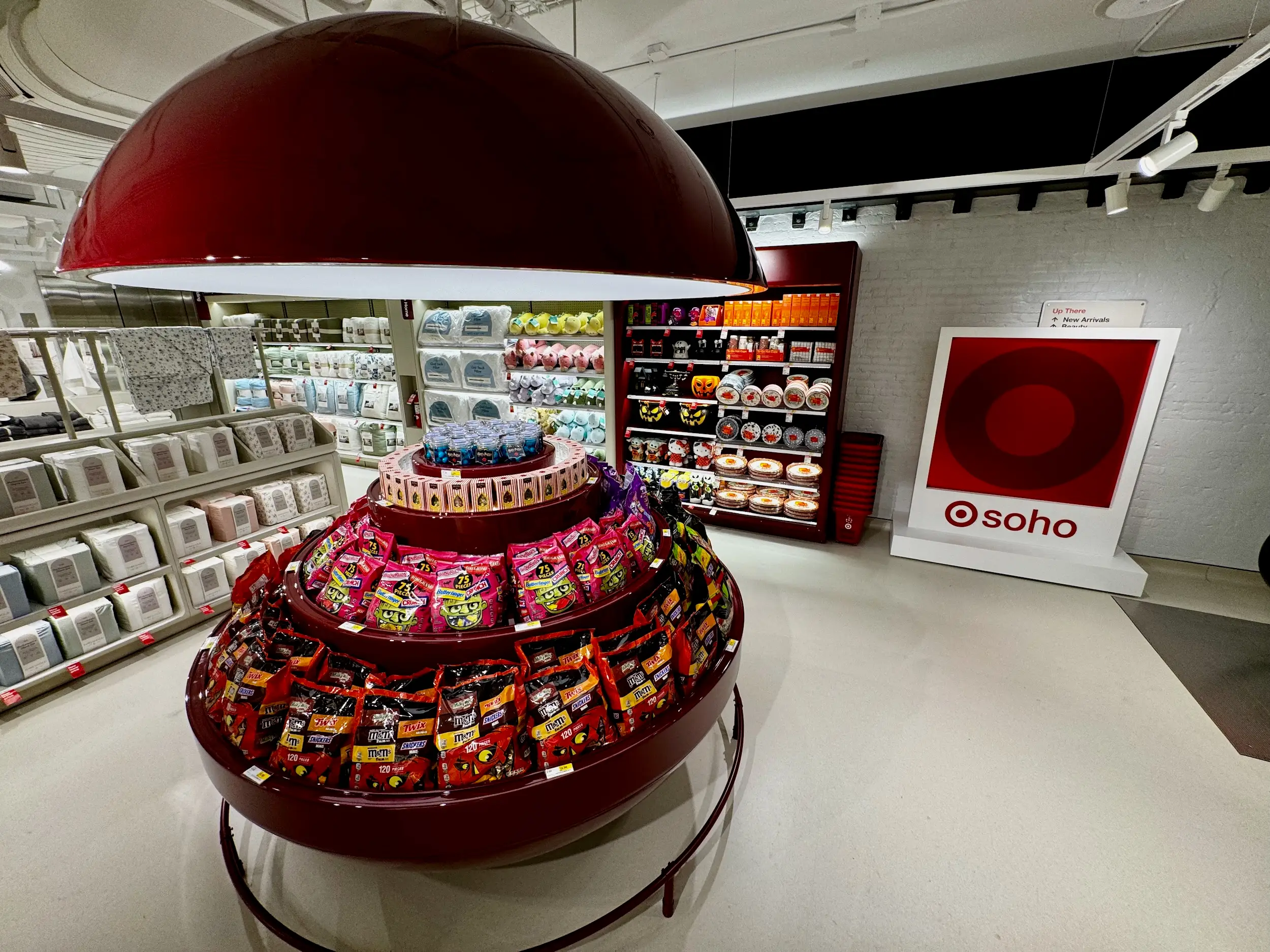 Target store interior with a circular candy display, bright shelving, large red ceiling fixture, and a “soho” sign.