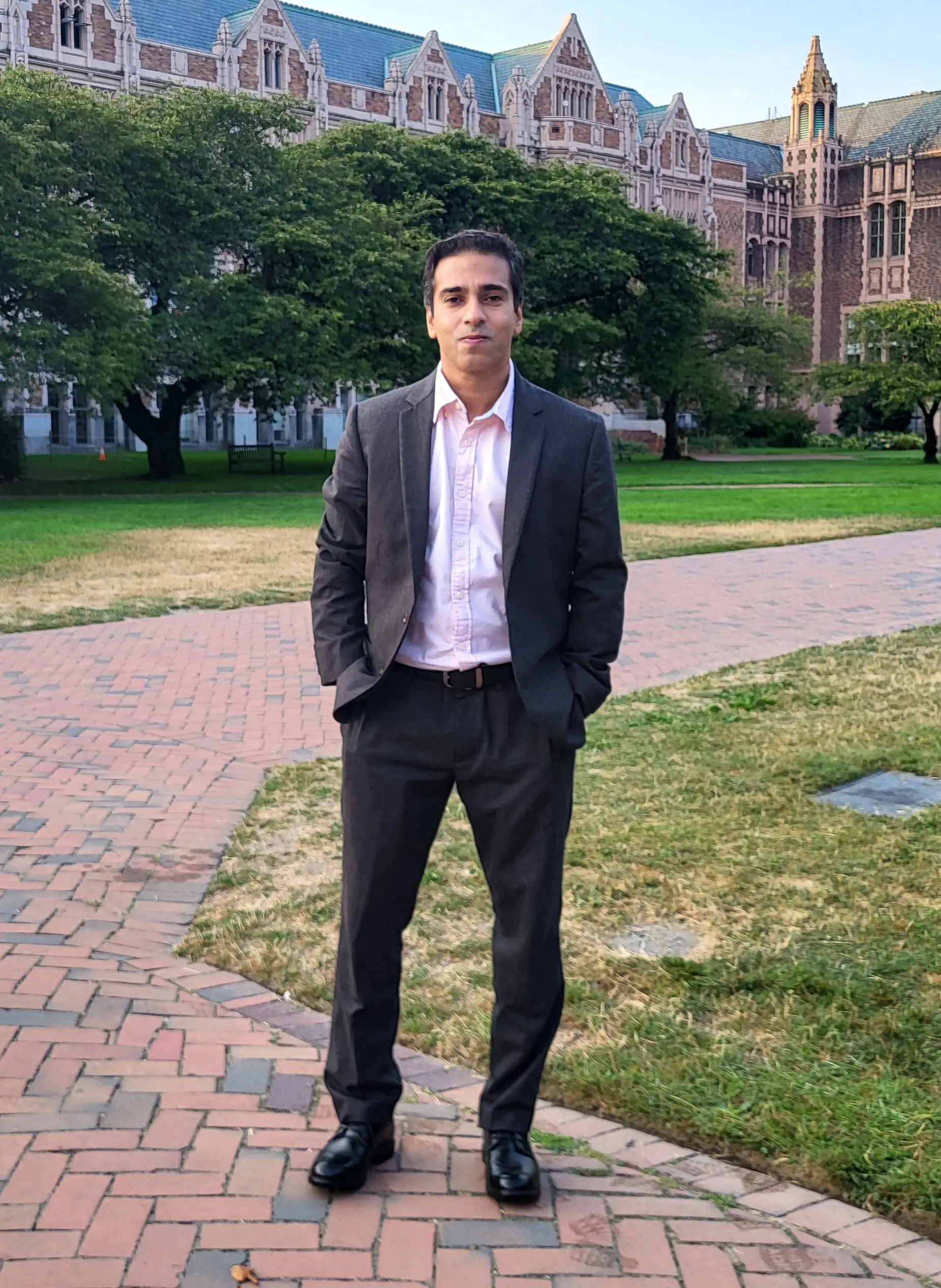 Upadhyaya is standing on his university campus, in front of a big building.
