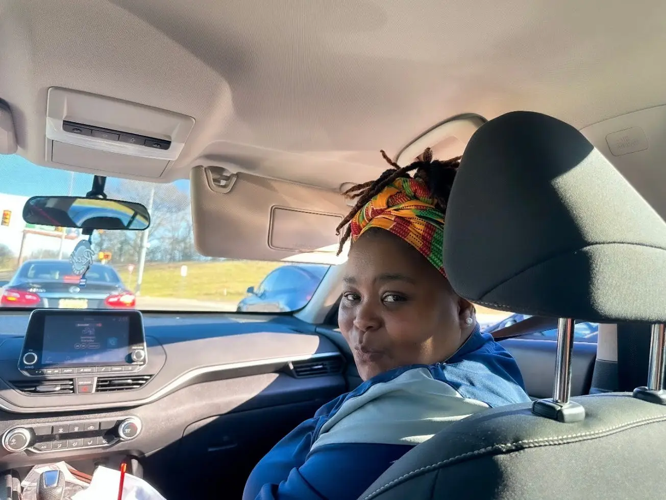 The author's mother sitting inside a car and smiling.