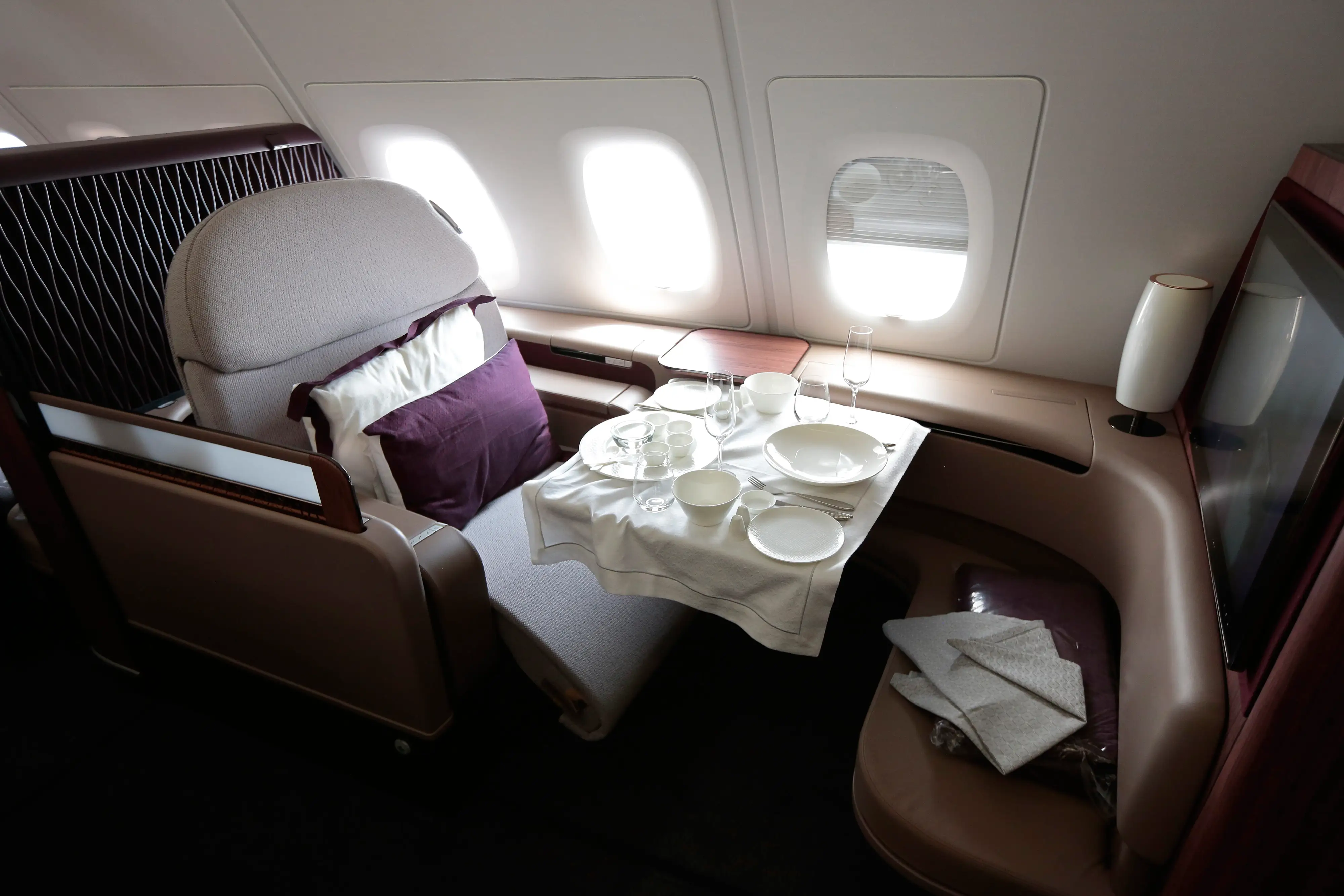 A dining set sits on the table of a First Class passenger booth inside an Airbus SAS A380 aircraft, operated by Qatar Airways