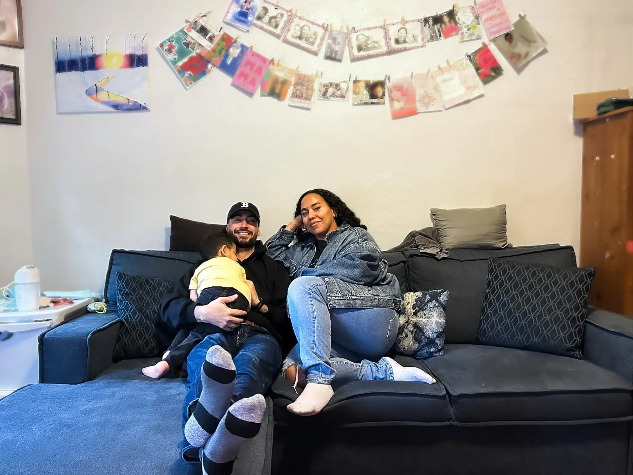 Yaritza, her husband, and their son sit on a couch.
