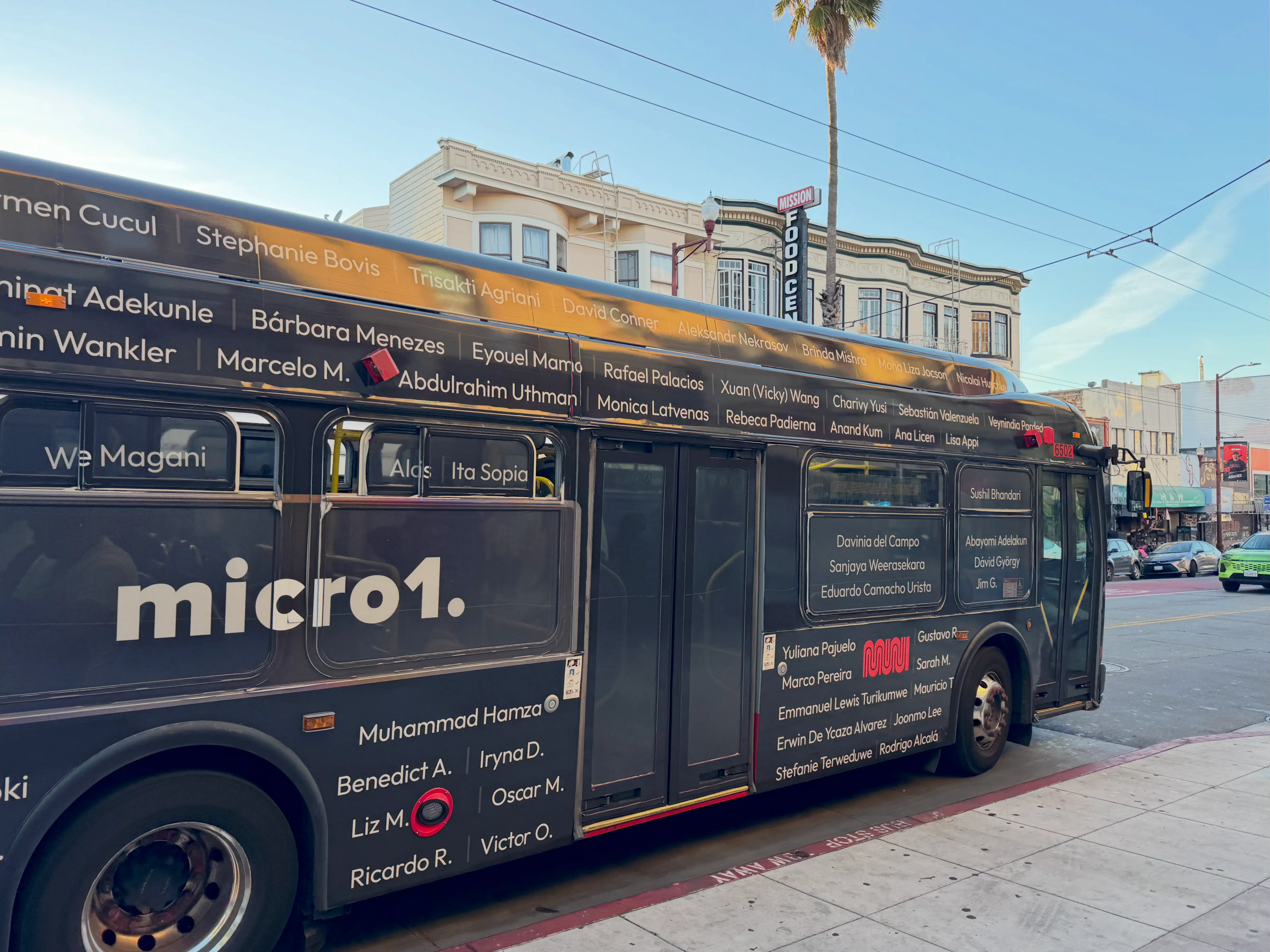A San Francisco Muni bus emblazoned with Micro1 advertising drives on Mission Street.