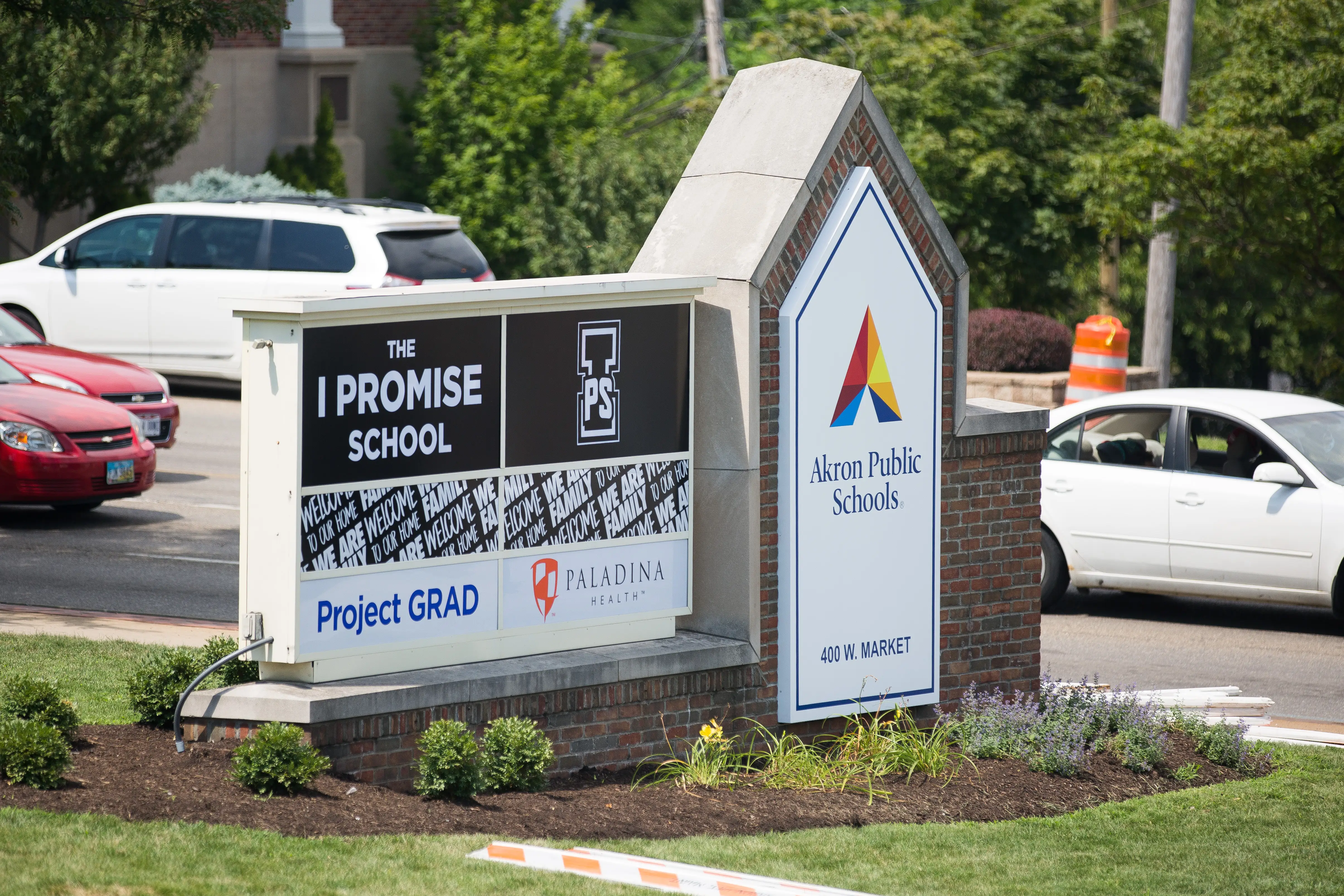 Signage for THE I PROMISE SCHOOL and Akron Public Schools stands beside a landscaped roadside entrance.