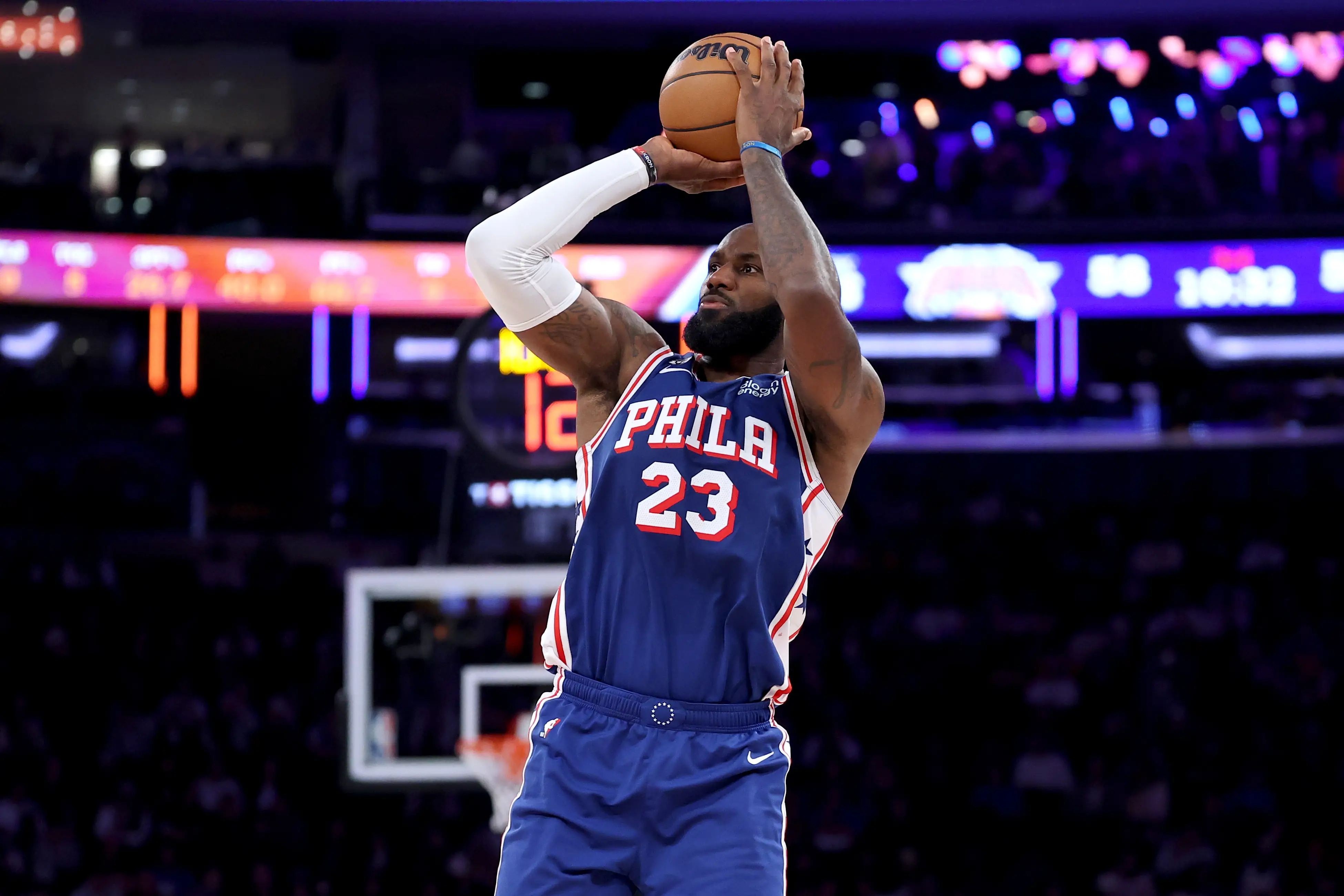 LeBron James, in a blue PHILA number 23 uniform, shoots a basketball in an arena.