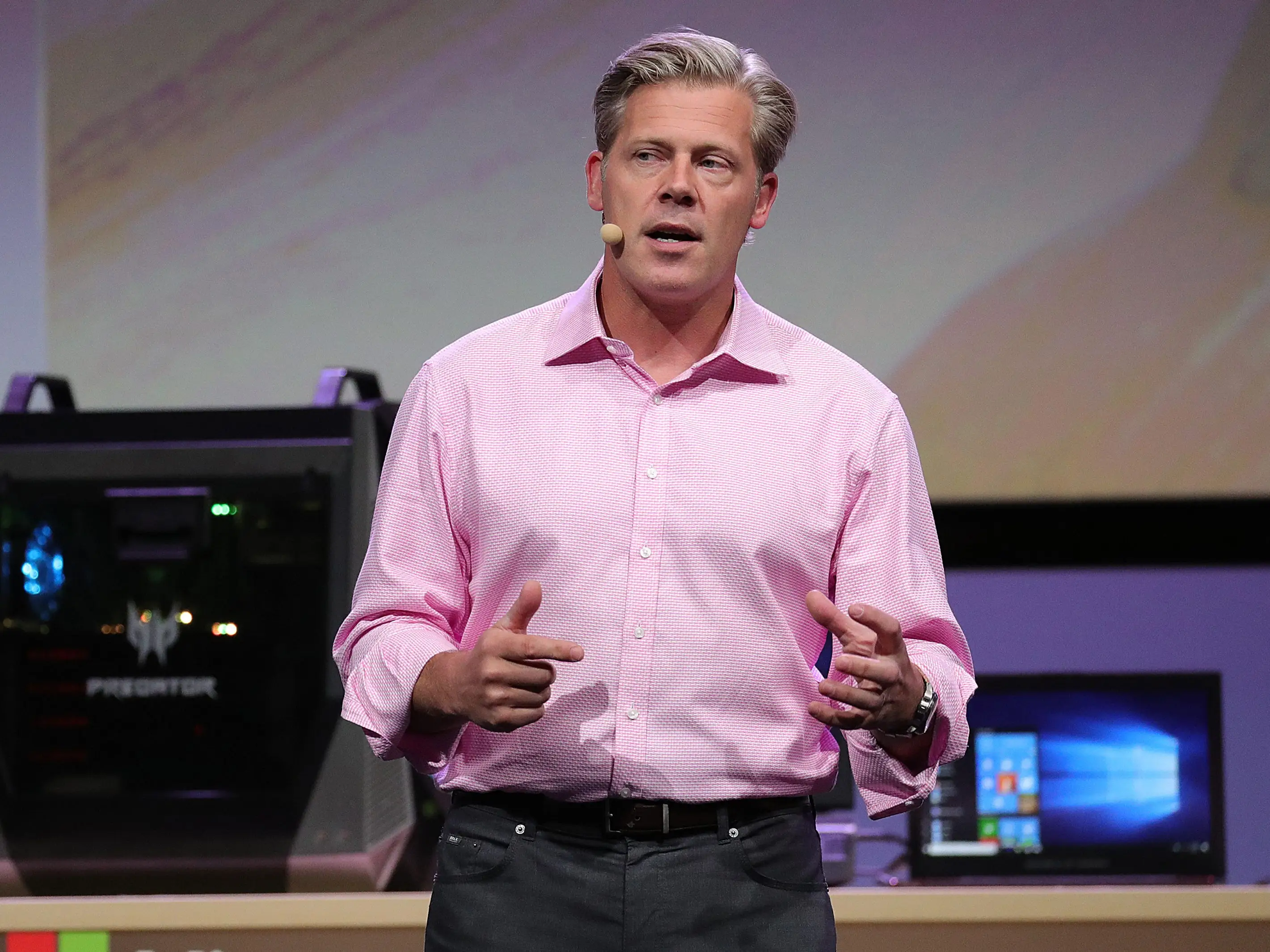 Nick Parker presenting onstage, wearing a pink collar shirt.