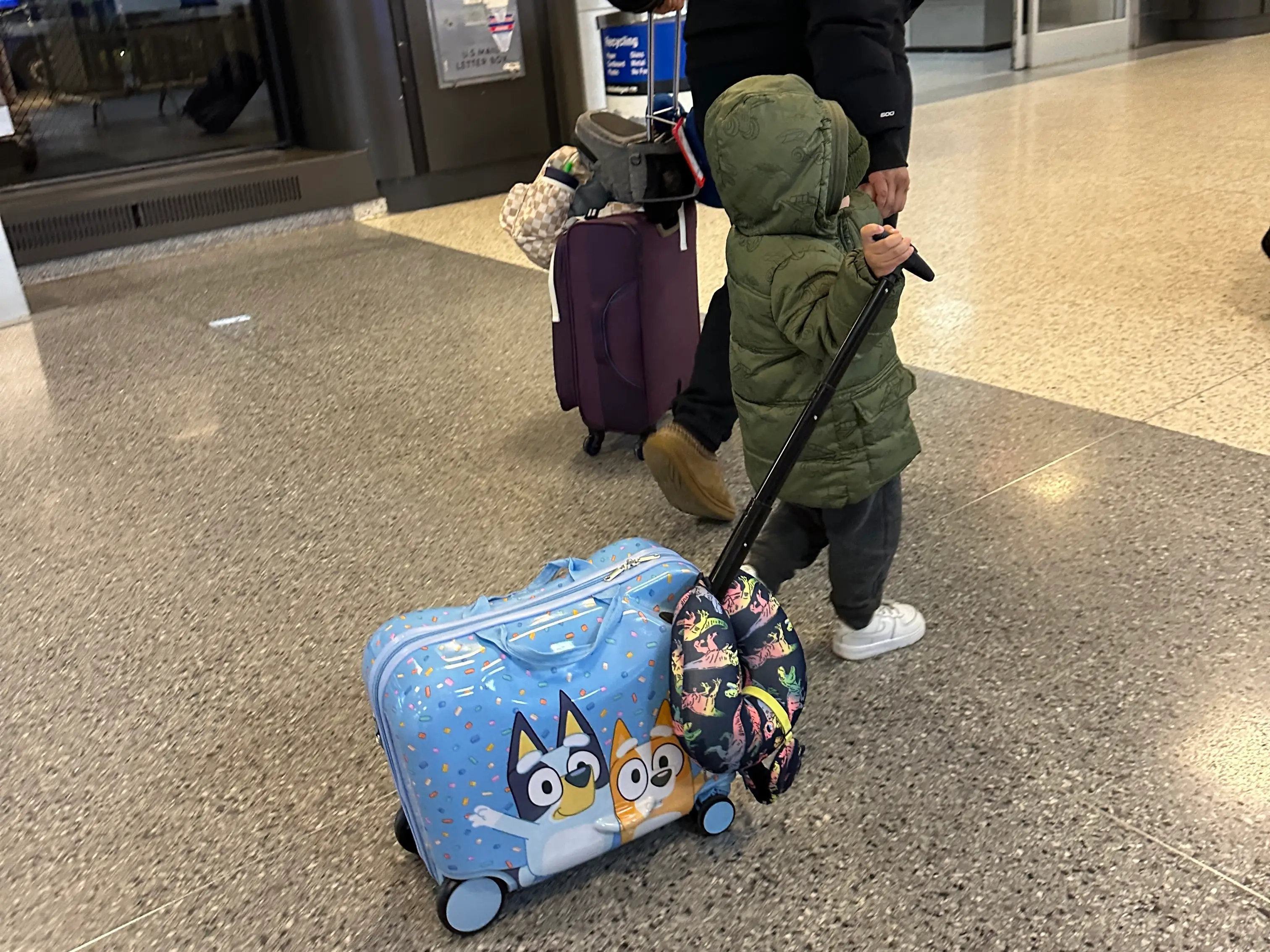 Yaritza's young son pulls a small Bluey suitcase in the airport.