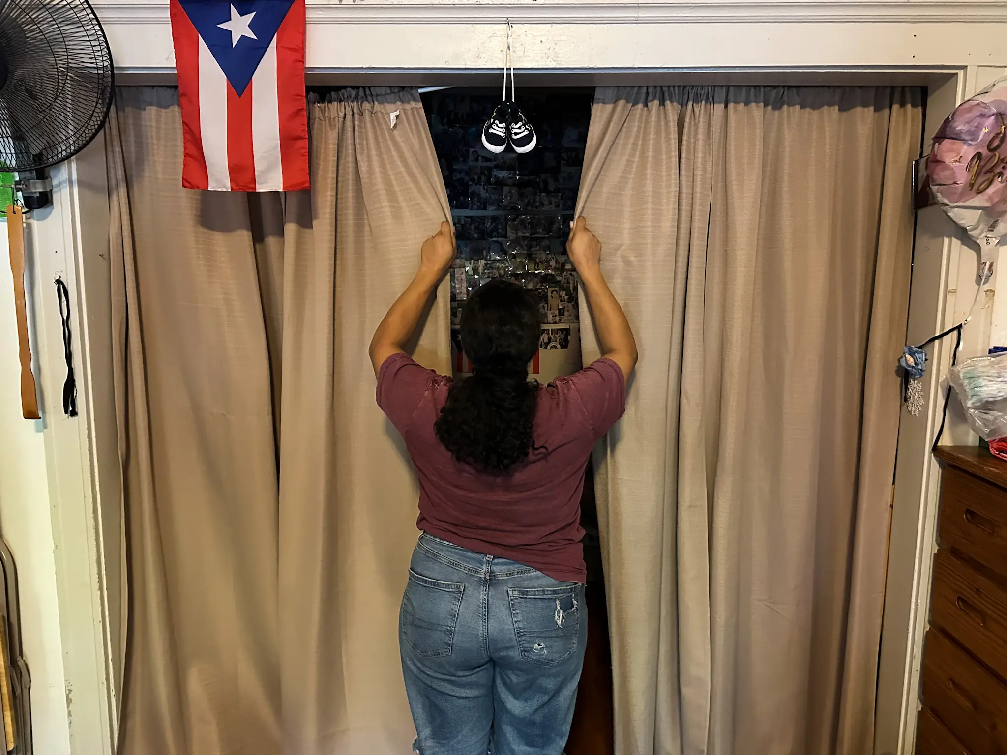 Yaritza closes the curtains separating the living room from the rest of the apartment.