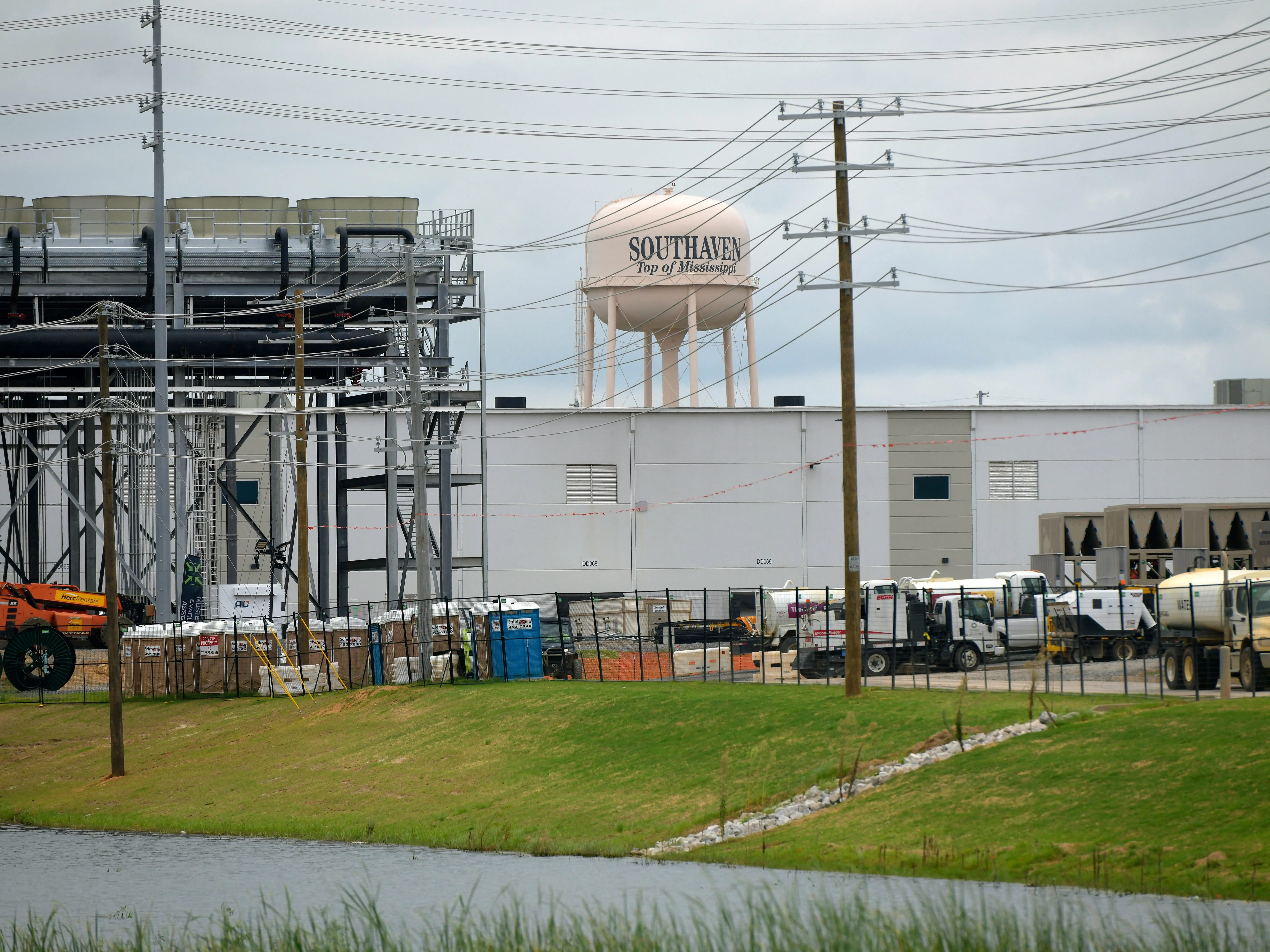 Industrial facility grounds with utility poles, work trucks, and a Southaven water tower behind a large white building.