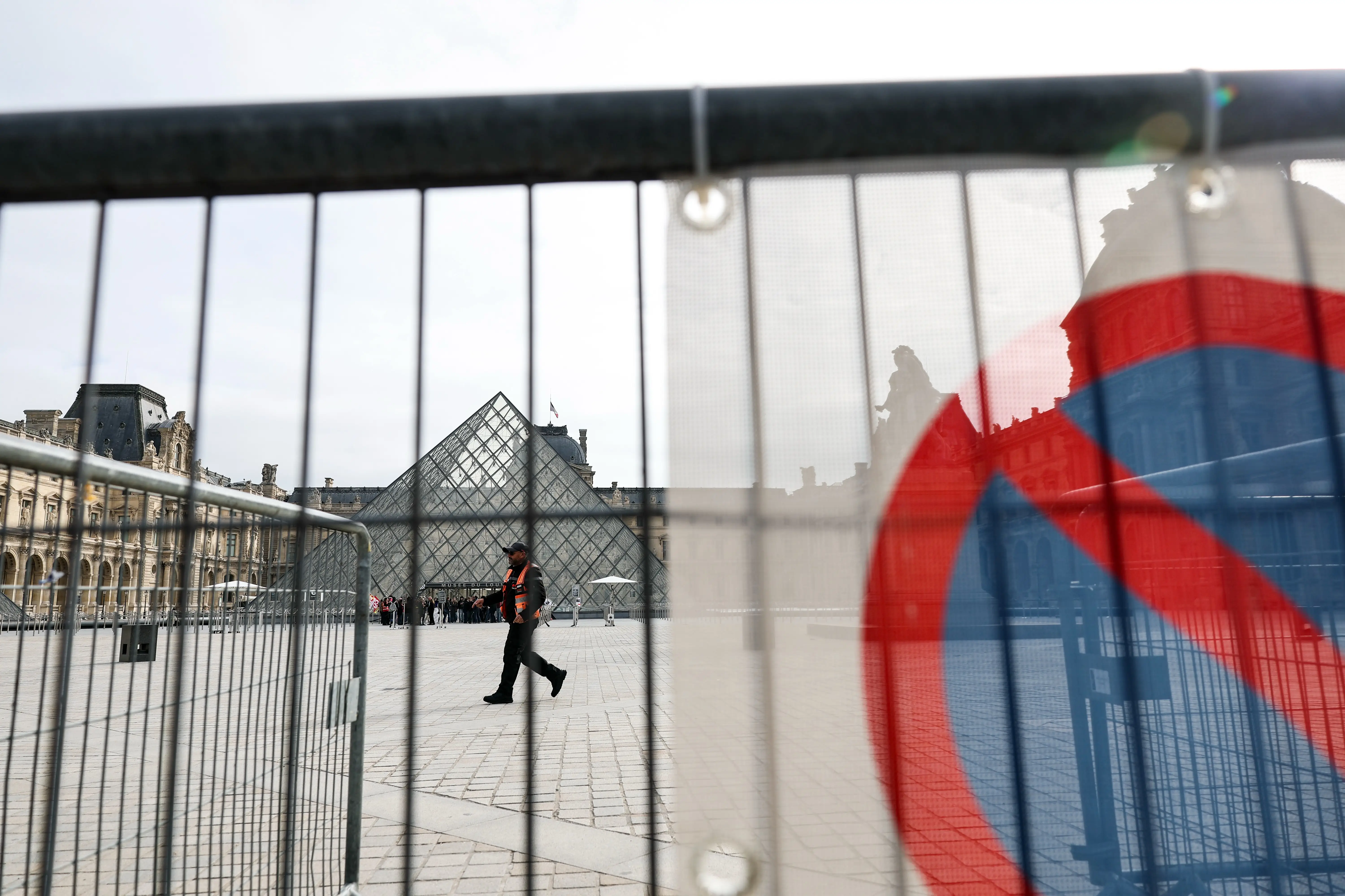 A do not enter sign and a barricade in front of the glass pyramid of the Louvre