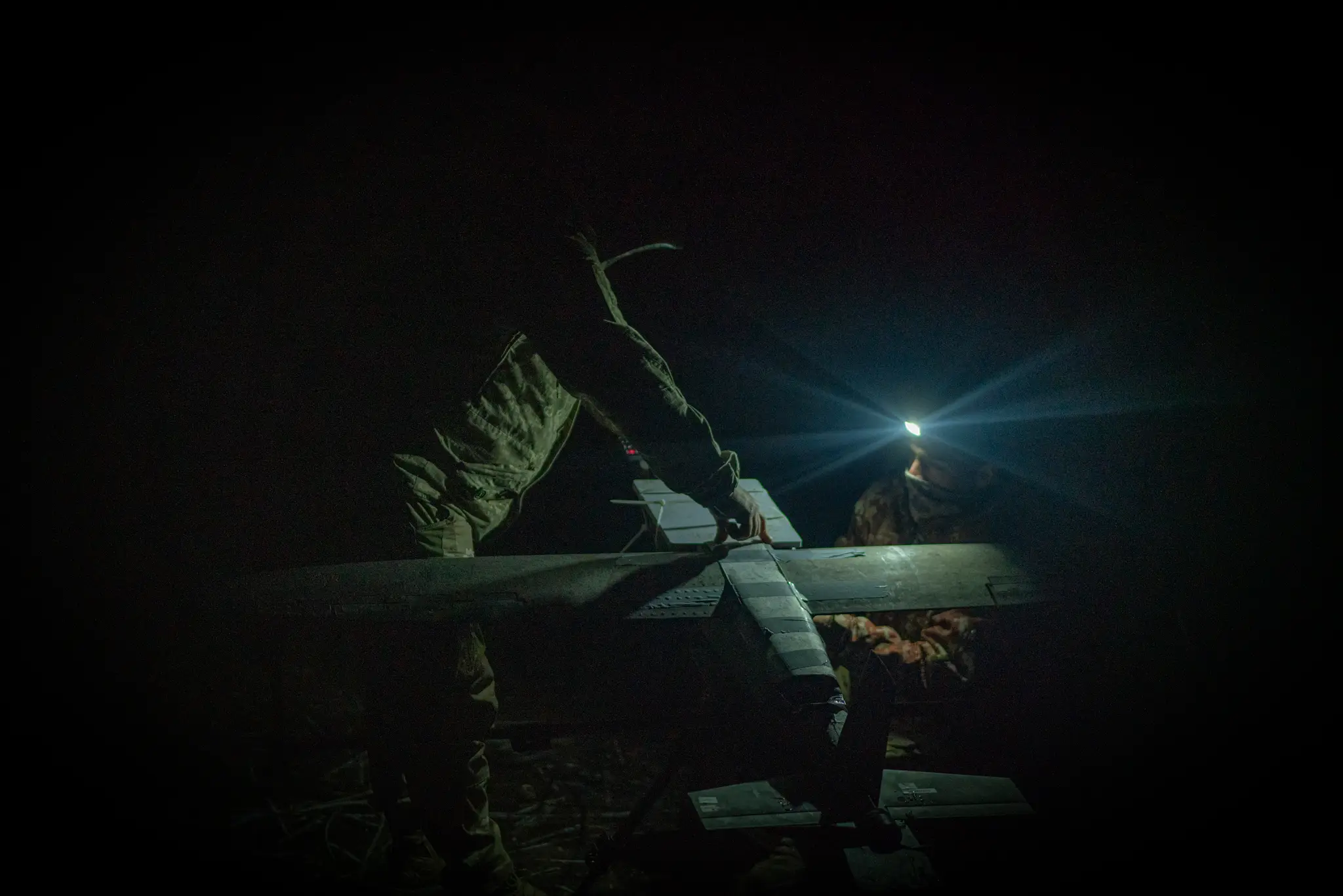 Ukrainian troops prep a mid-range Hornet drone at night.