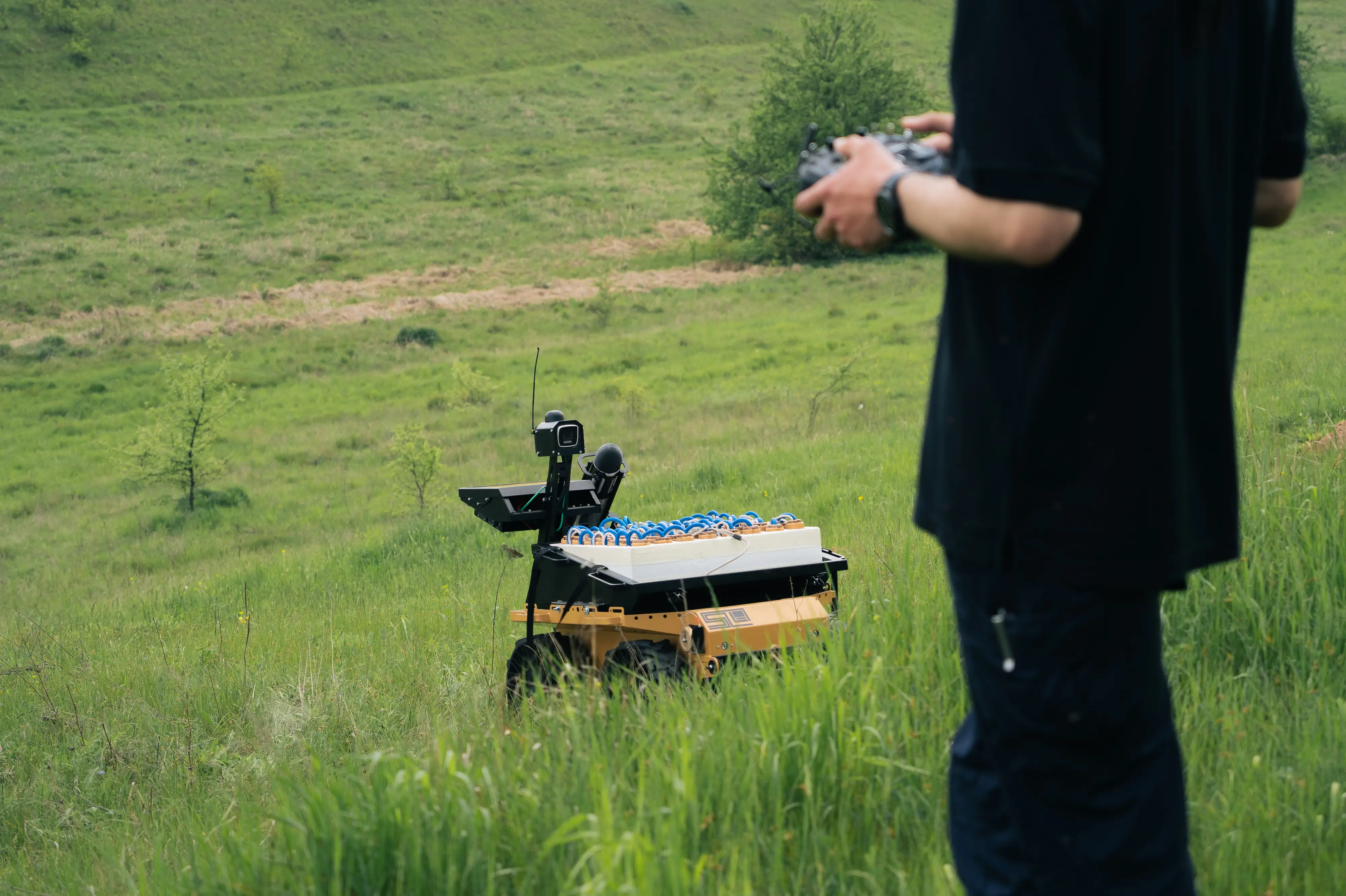 A Ukrainian drone operator holds a controller next to a ground drone.