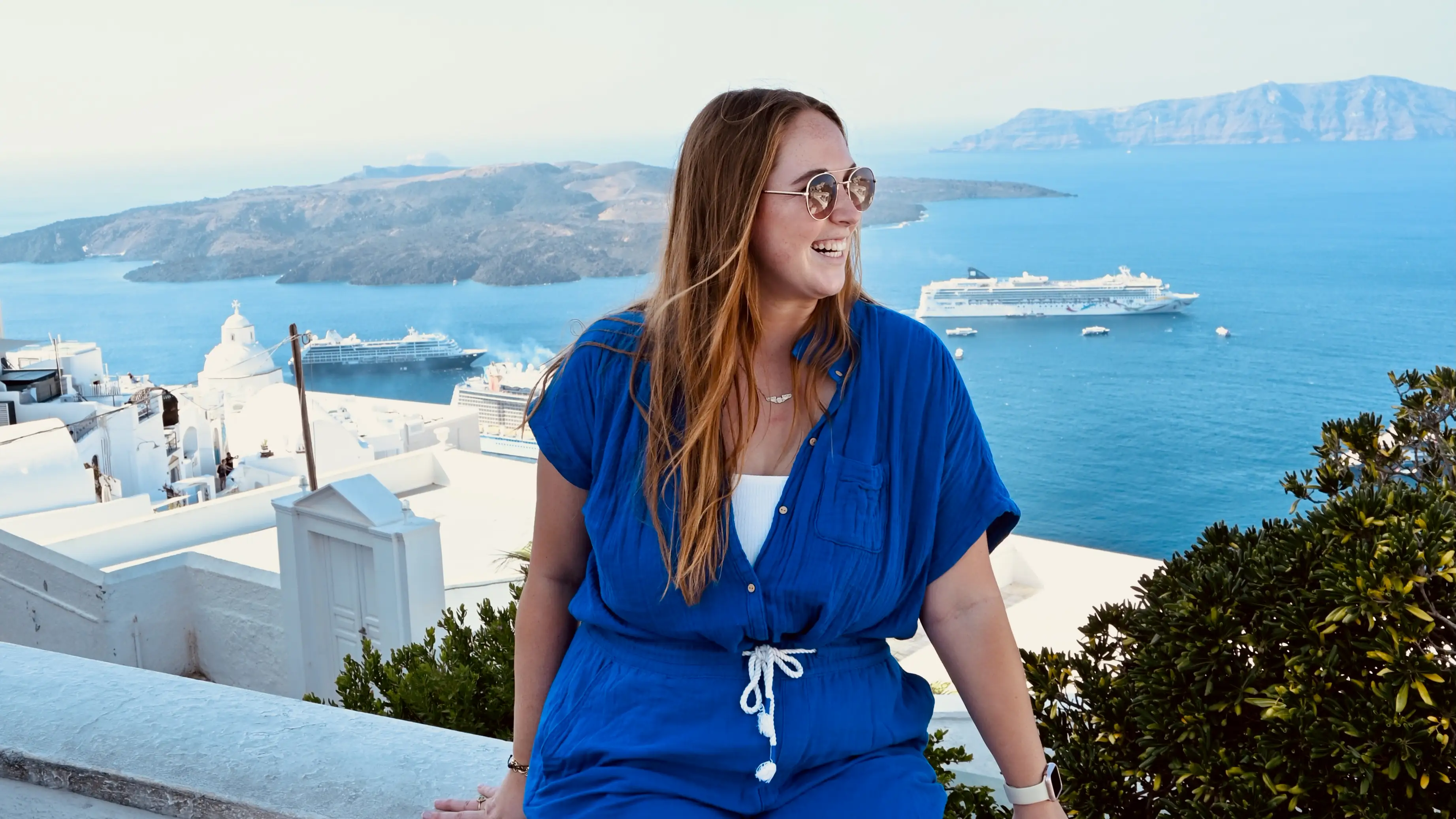 Woman smiling with view of cruise ship, Santorini behind her