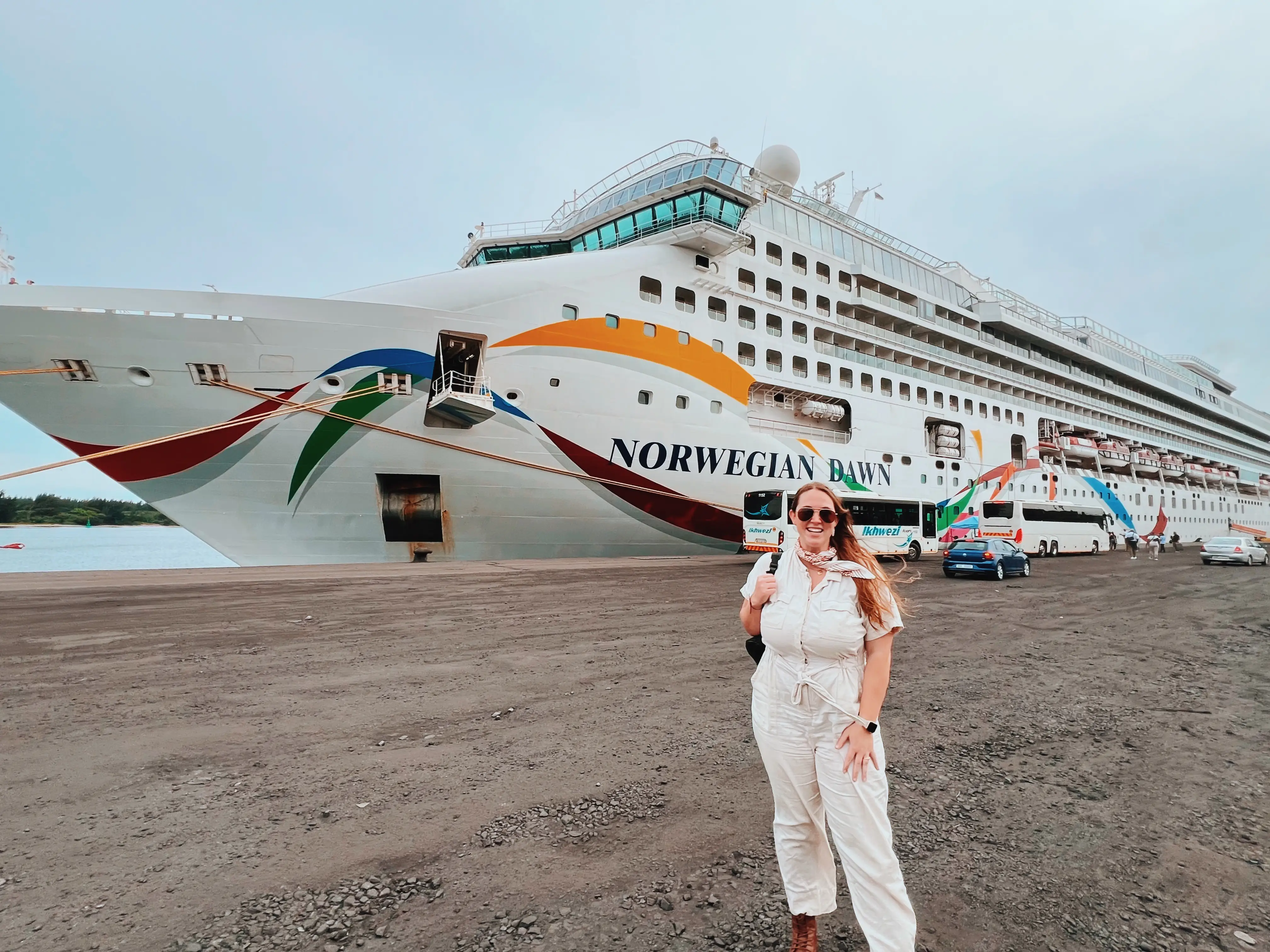 Woman standing in Rciahrds Bay gravel port with view of Norwegian cruise ship behind her