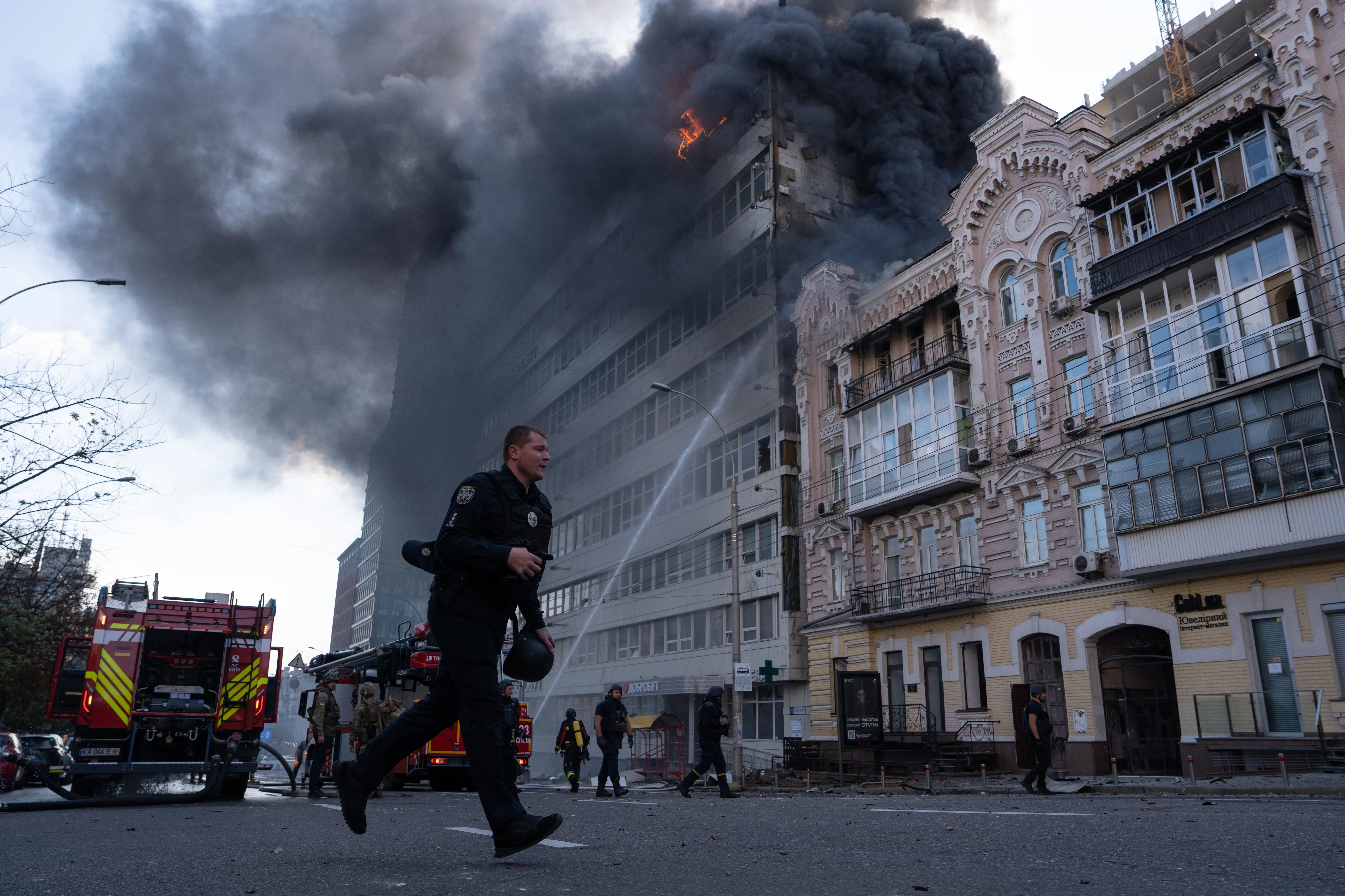 A firefighter runs as a building behind him burns.
