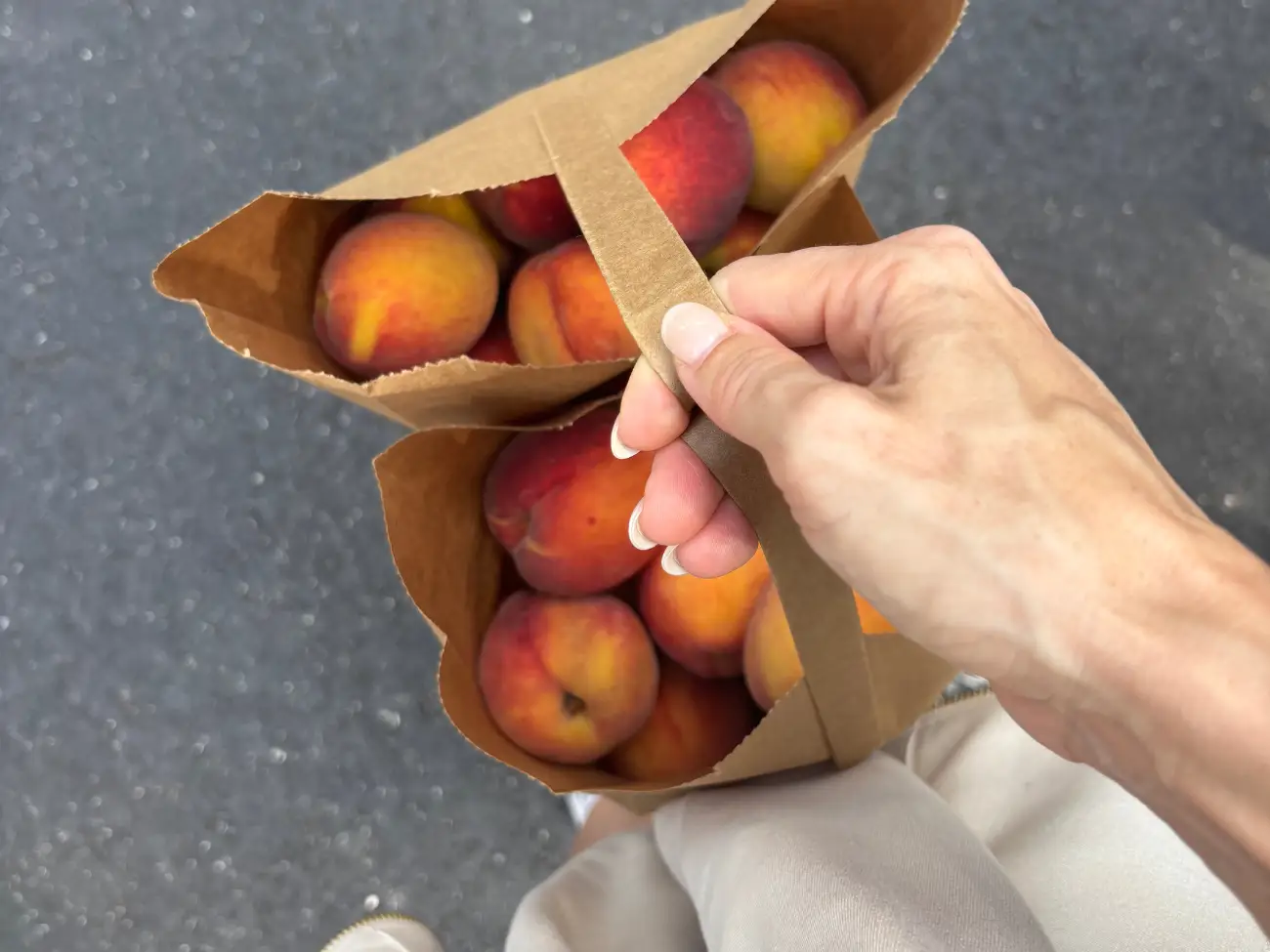 Jana carrying two bags of fresh peaches.