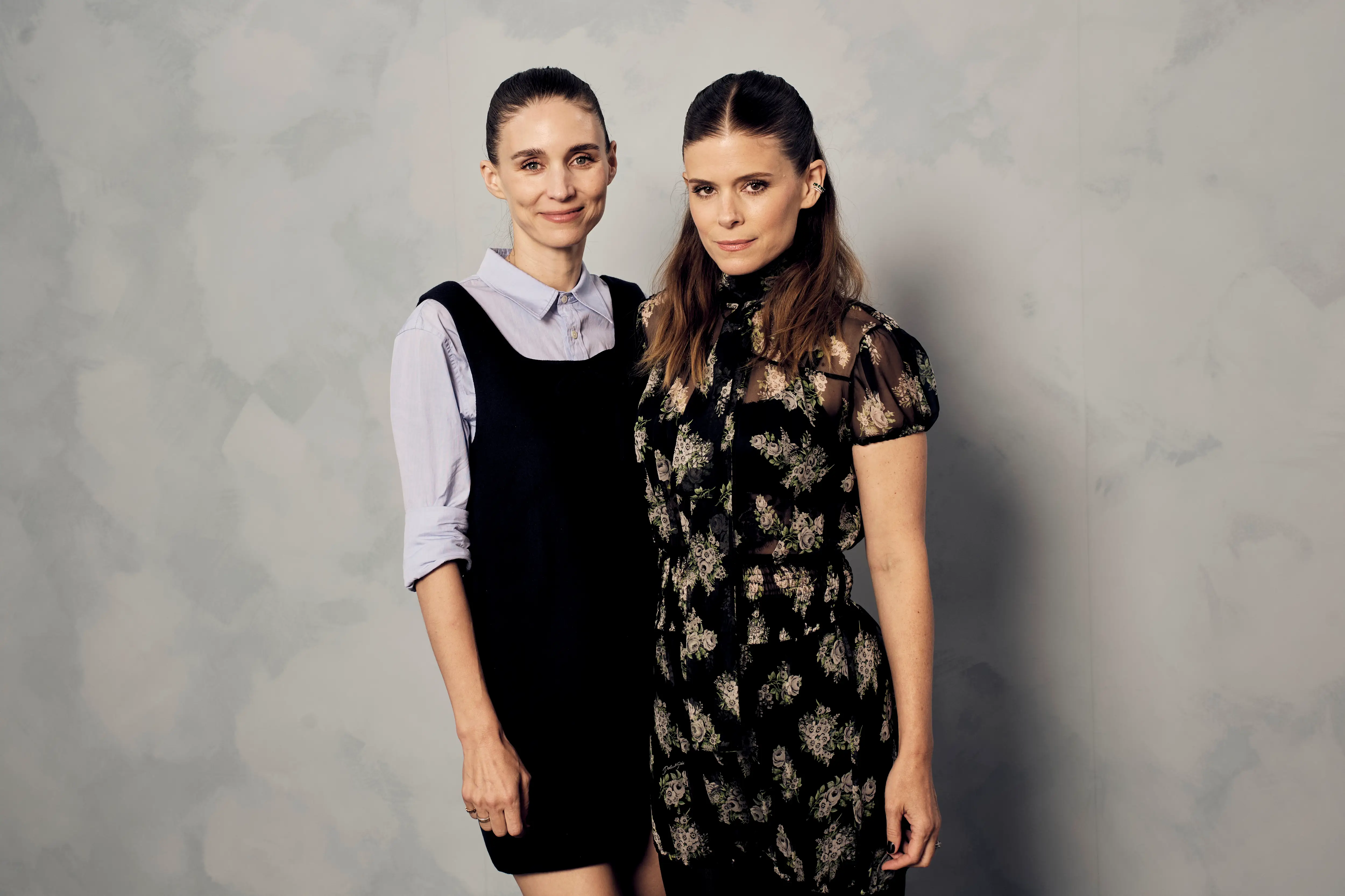 Kate and Rooney Mara stand side by side against a mottled gray studio backdrop.