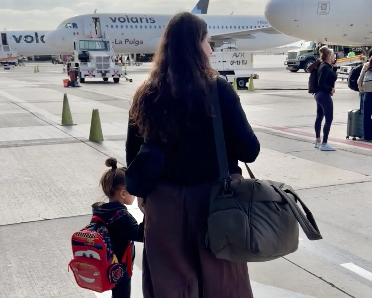 Woman holding child's hand near plane