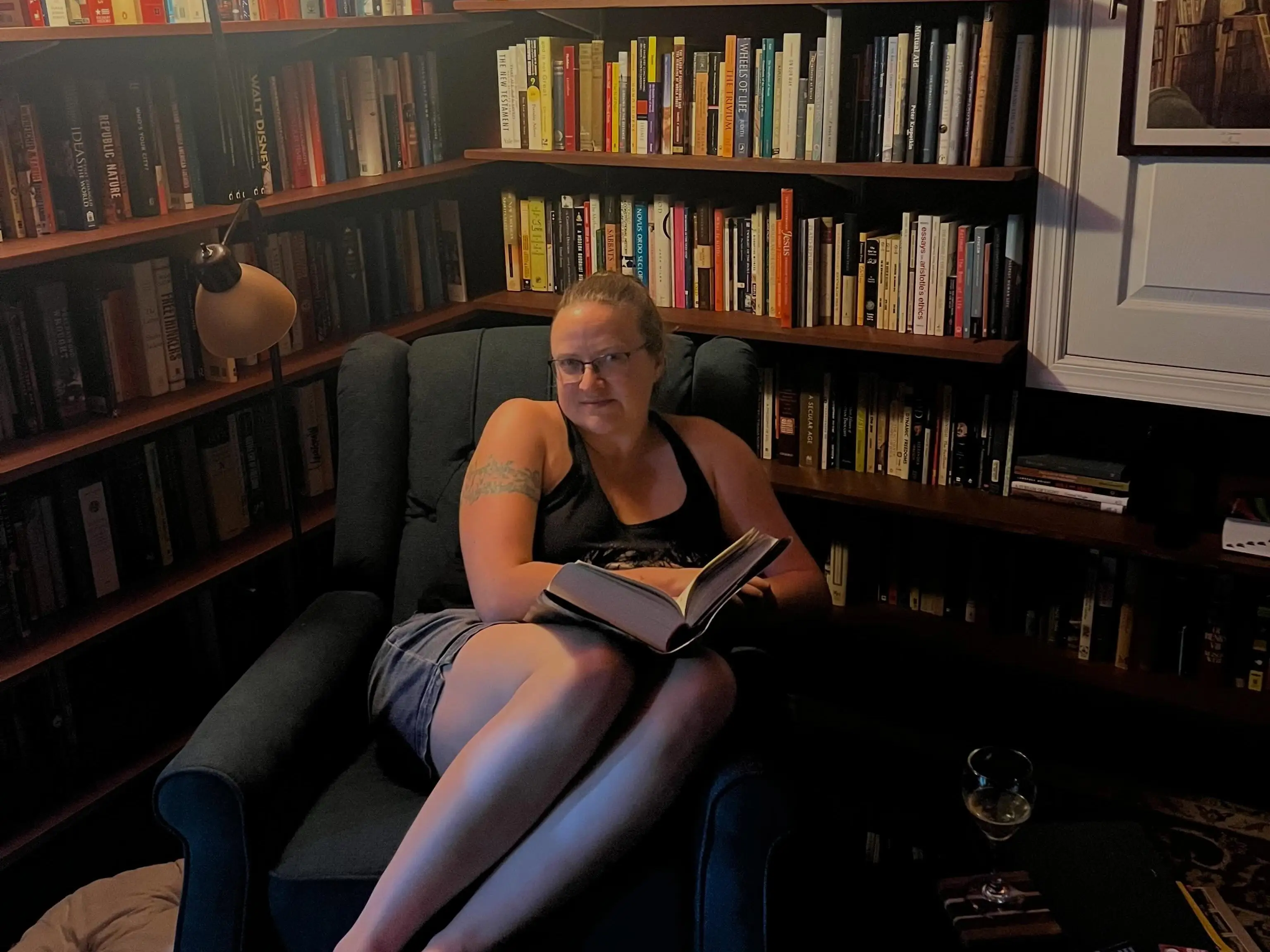 The writer's wife is sitting in the library in their home.