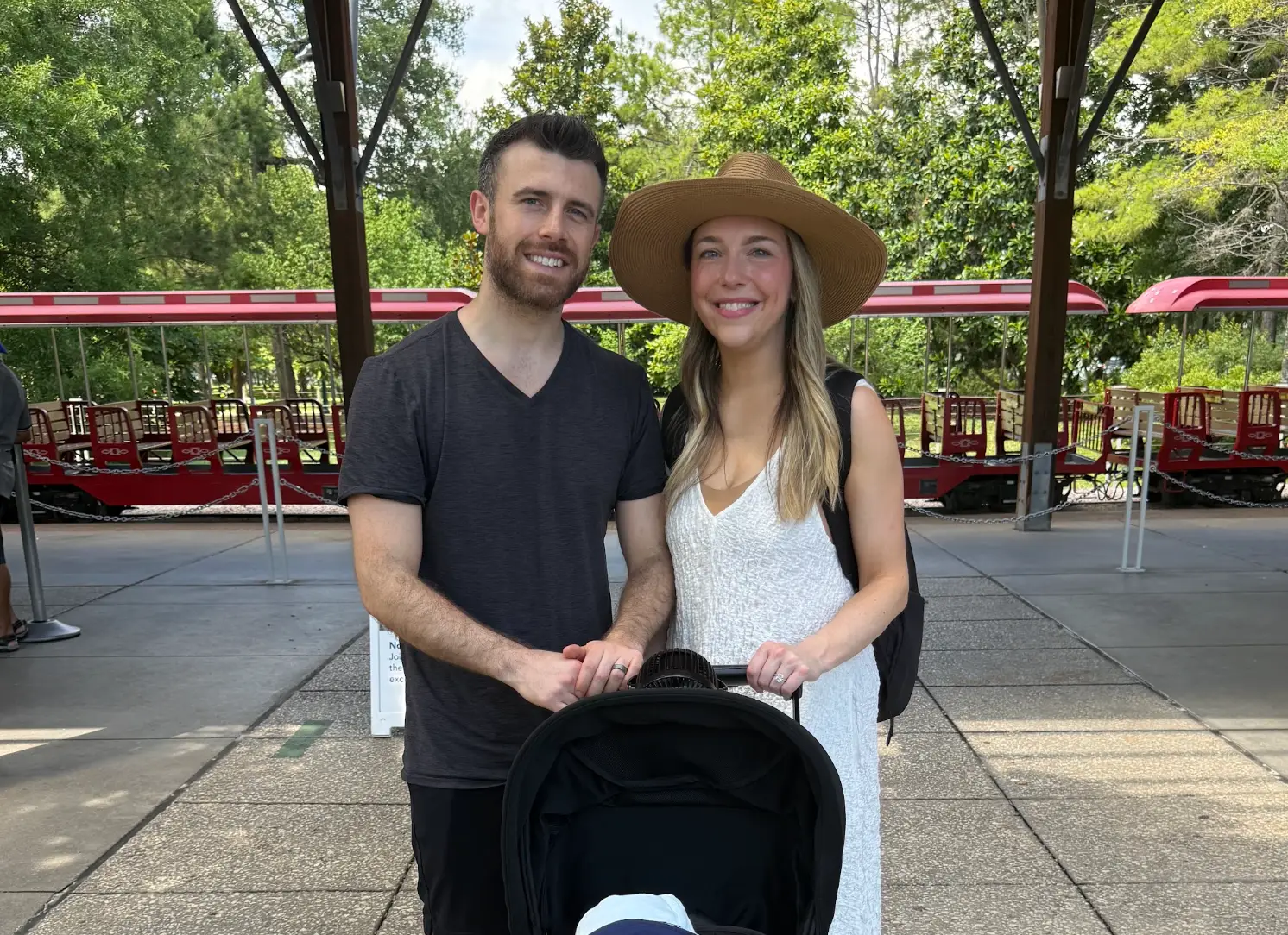 the writer, her husband, and a stroller in front of a trolley, with trees in the background.