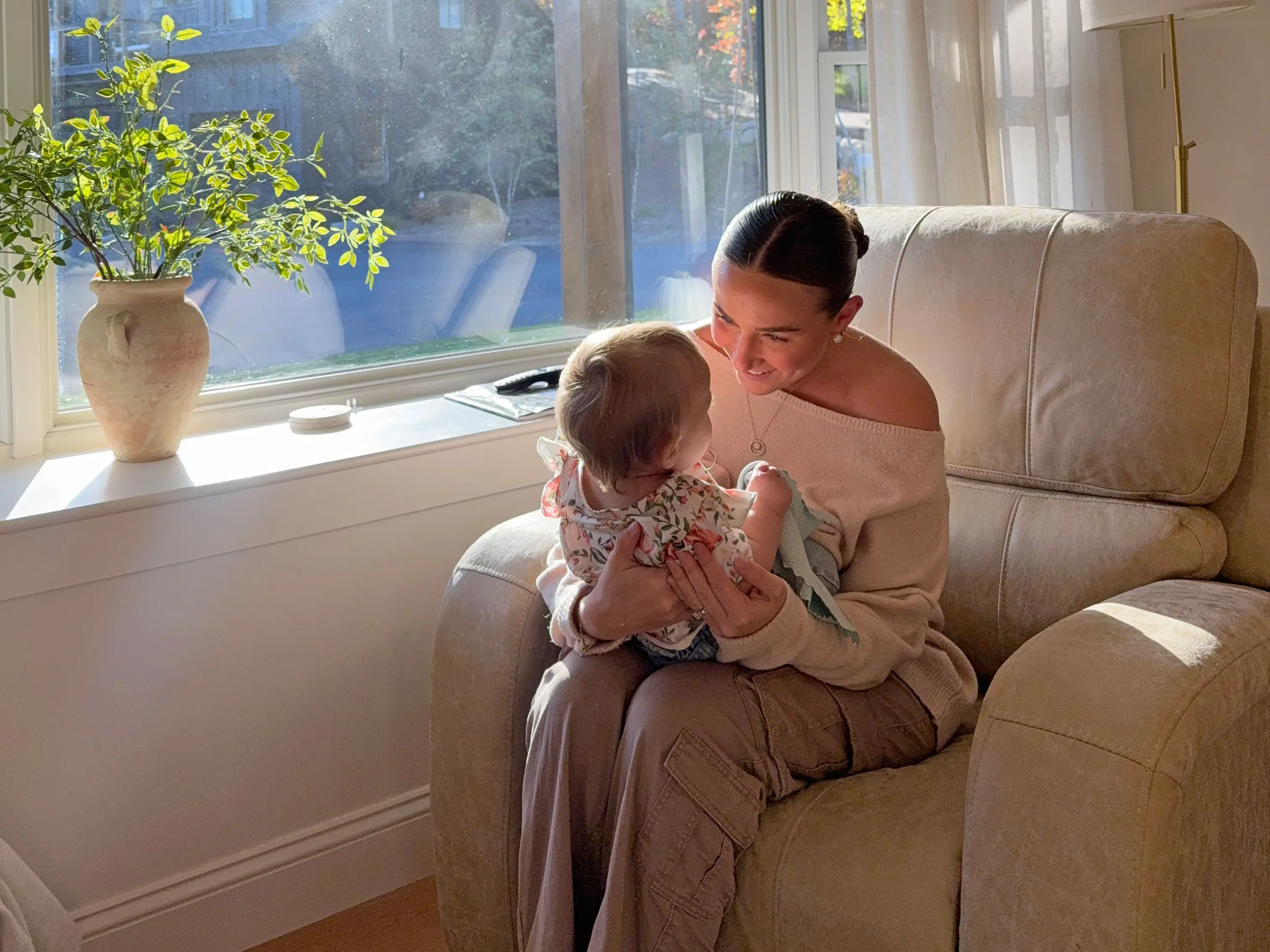 Taylor sits on a large chair and smiles at her young daughter.