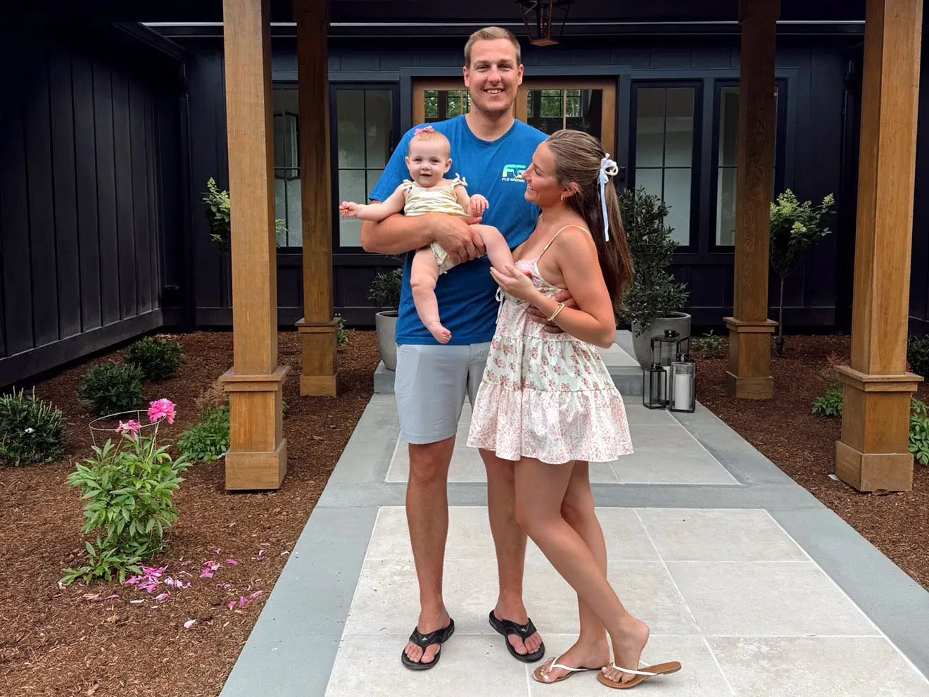 Taylor and her husband hold their young daughter in front of their house.