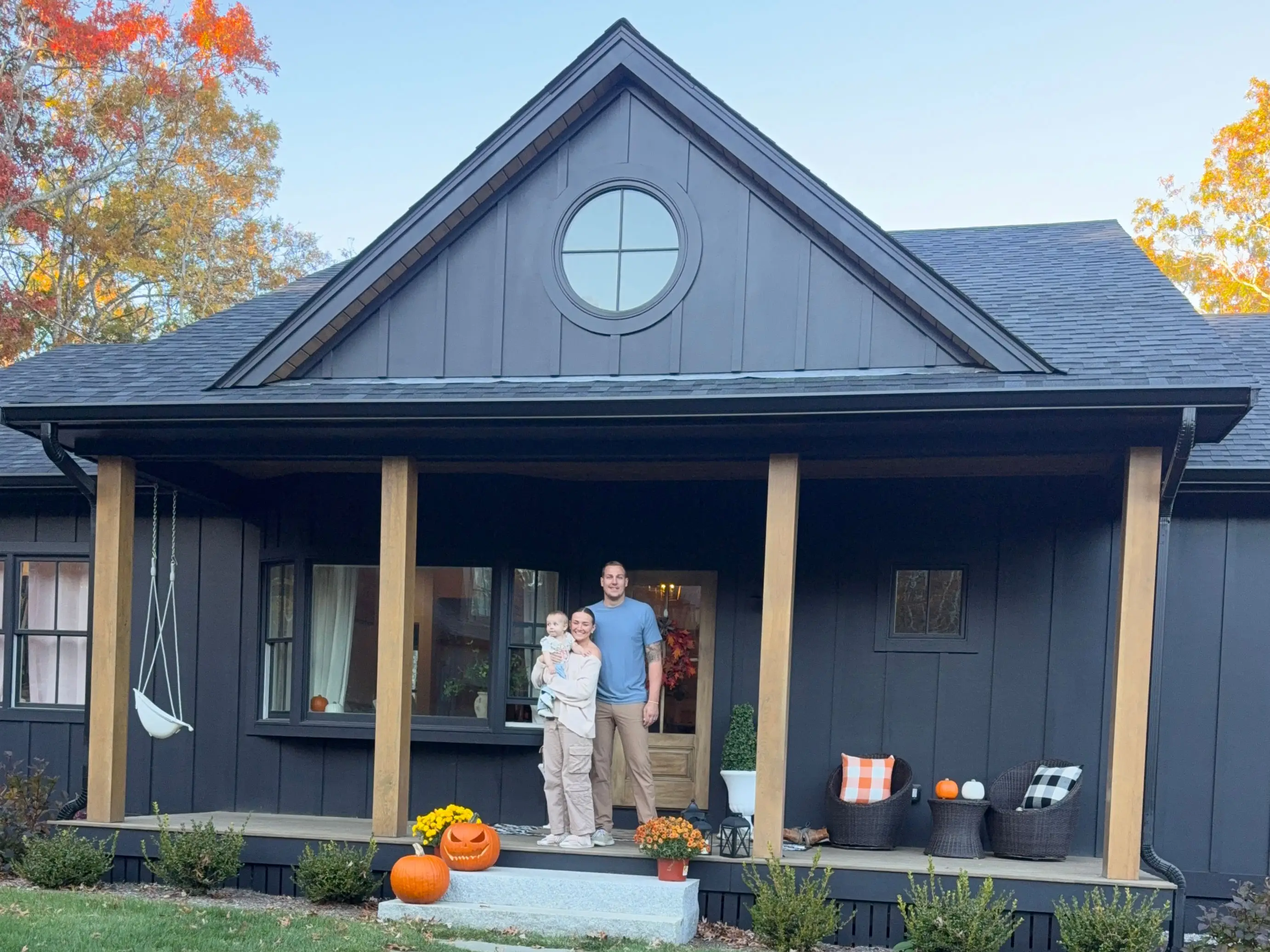 Taylor, her husband, and their daughter stand in front of their house.