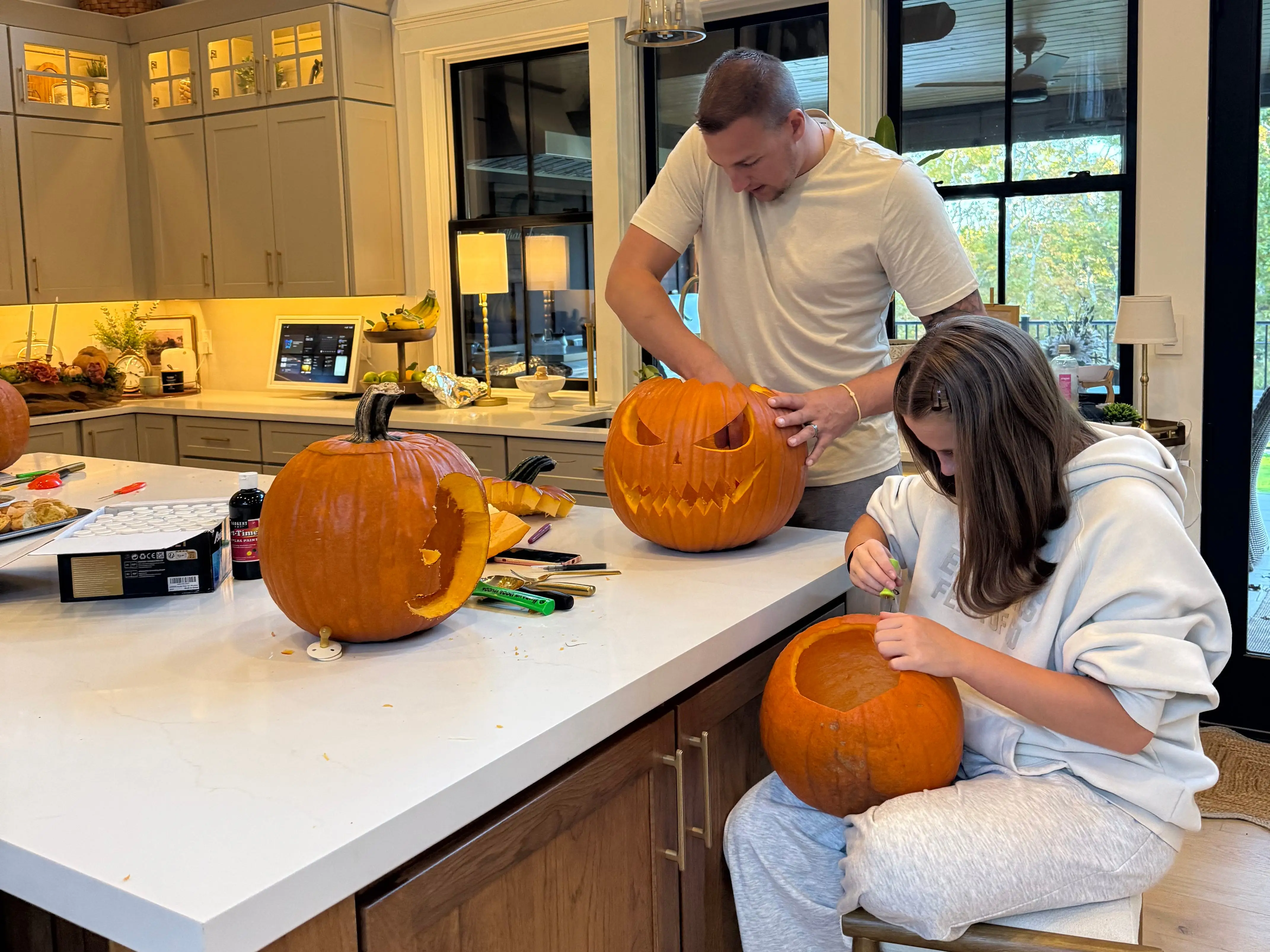 Taylor's husband and sister carving Jack-O-Lanterns in the kitchen.