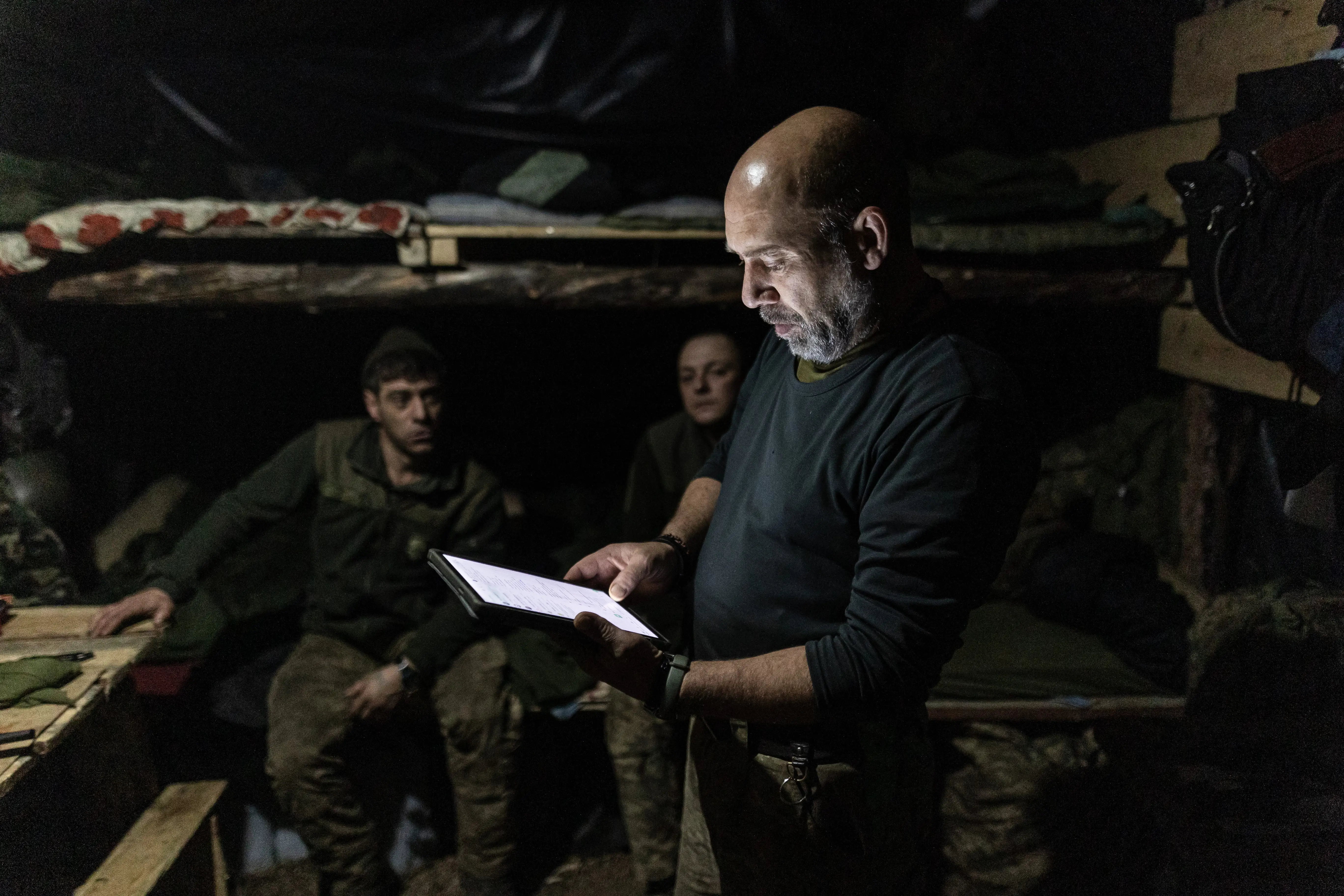 Ukrainian soldier looks at a tablet in a shelter.