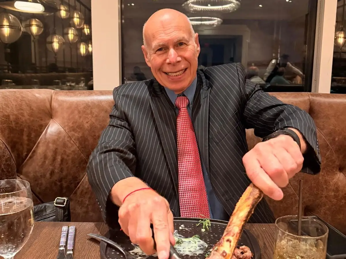 An older man in a restaurant wearing a pin-striped suit.
