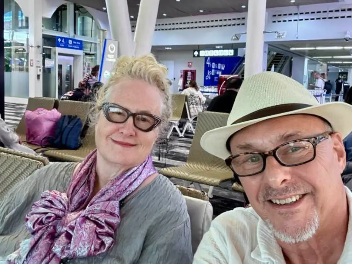 A couple taking a photo in a waiting area of a terminal.