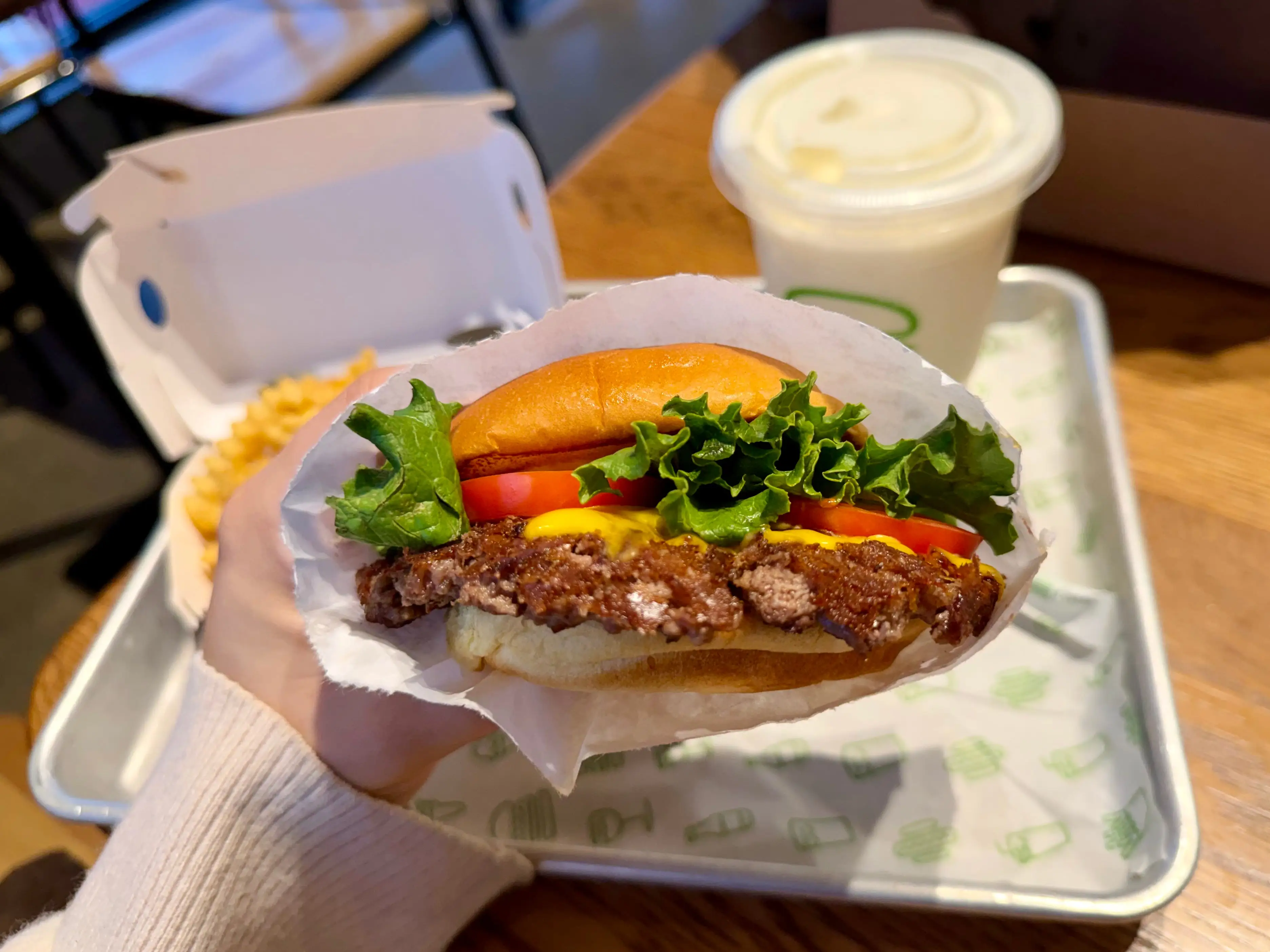 Amanda holds a cheeseburger with lettuce and tomato.