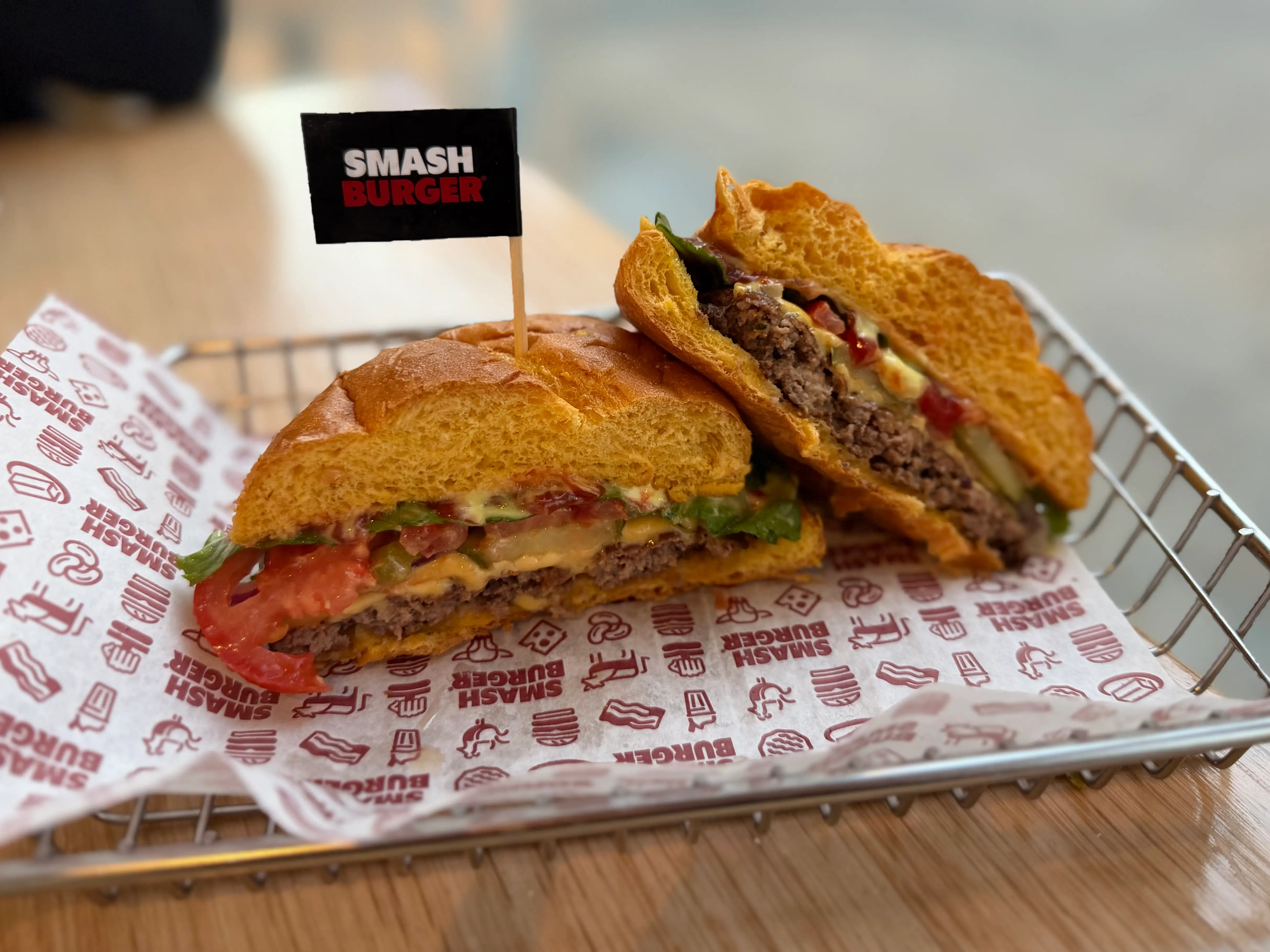 A cheeseburger with American cheese, lettuce, tomato, and sauce, that's been sliced in half.