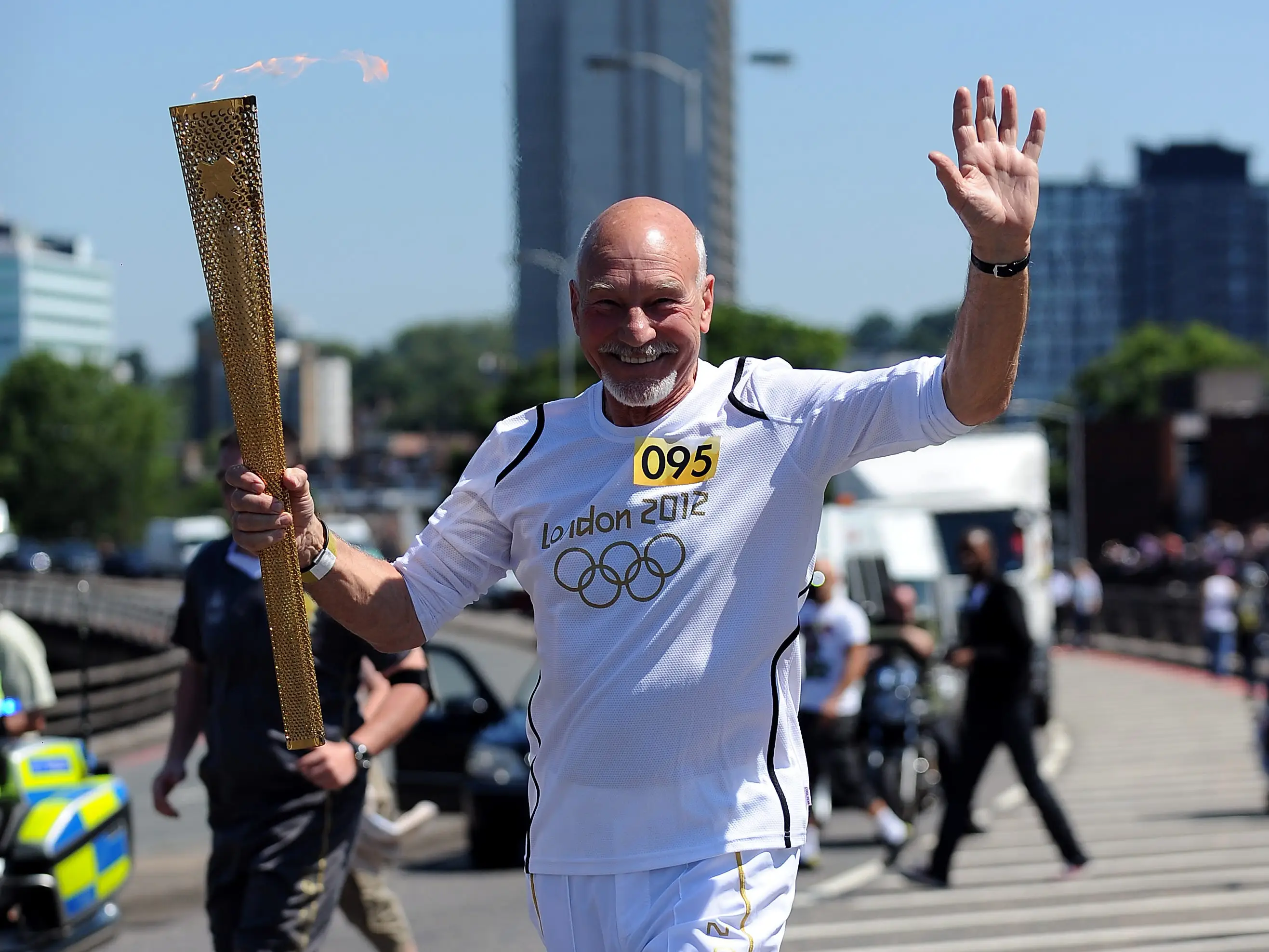 In this handout image provided by LOCOG, Torchbearer 095 Patrick Stewart carries the Olympic Flame on the Torch Relay leg through Croydon (London Borough) during Day 66 of the London 2012 Olympic Torch Relay on July 23, 2012 in London, England.